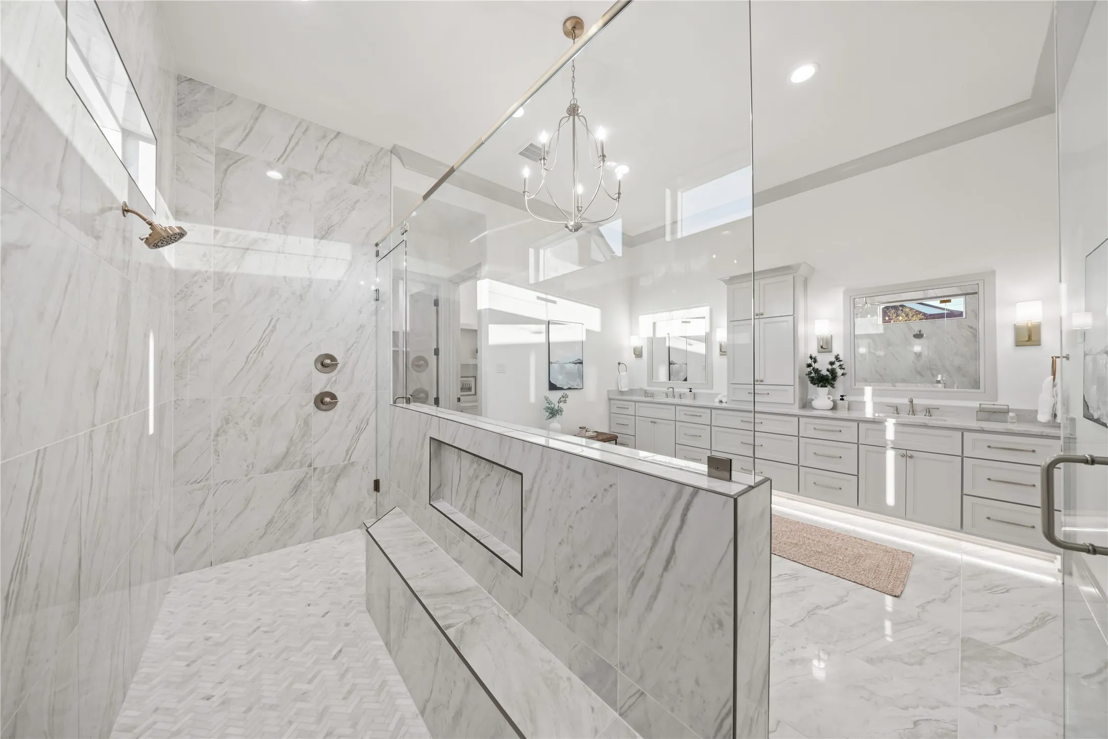 Spacious bathroom featuring a large glass-enclosed shower with full-height marble-look tiling and a built-in bench