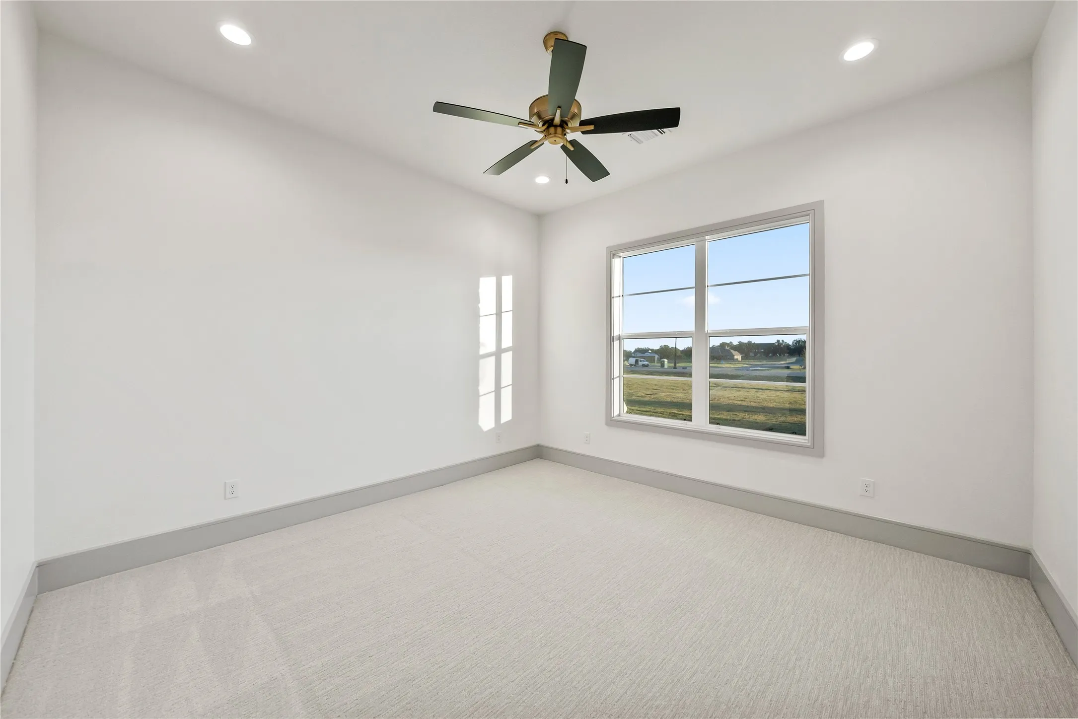 Light-filled room featuring a large window, recessed lighting, and a ceiling fan with gold-tone accents