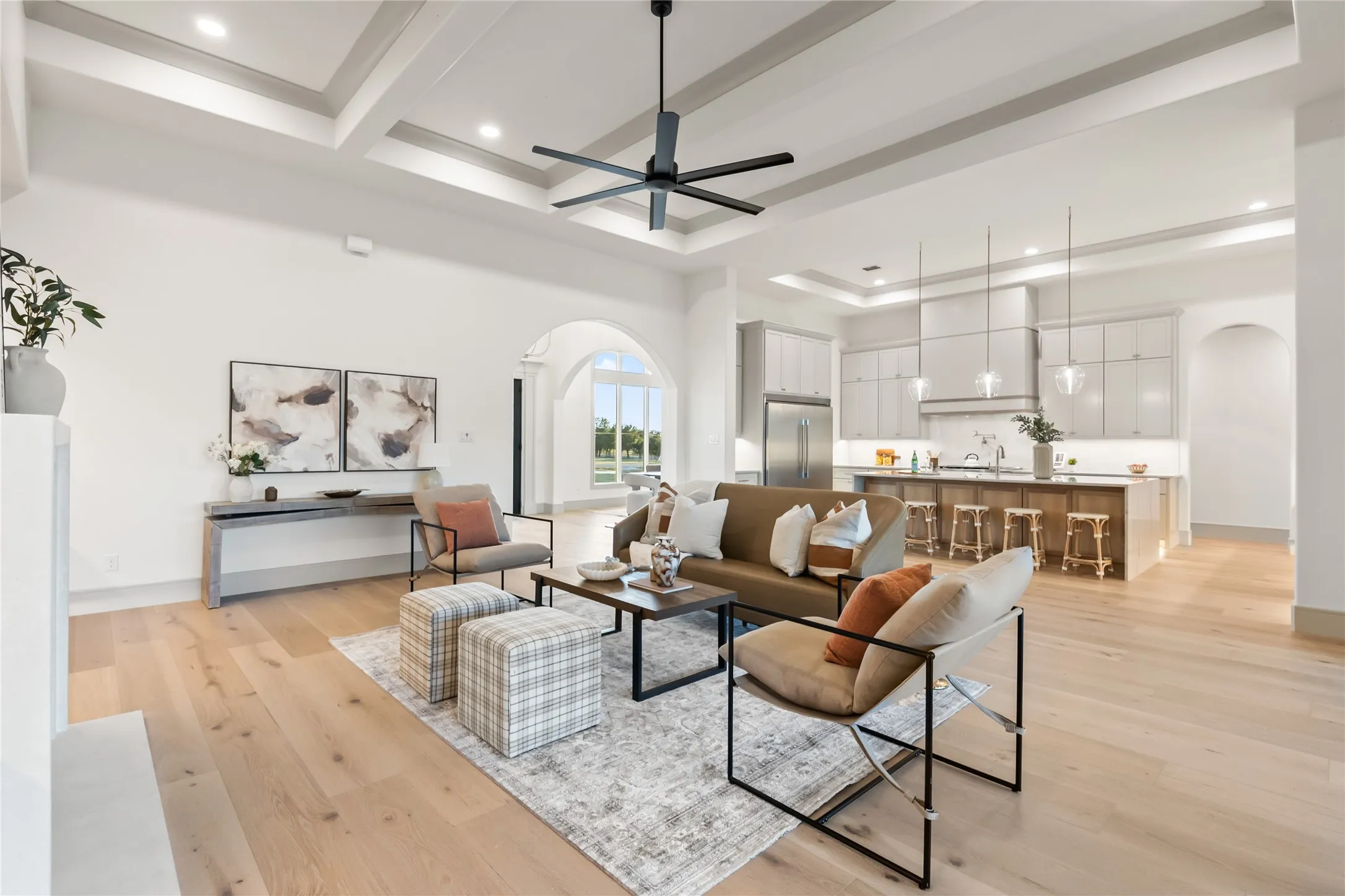 Expansive interior featuring light wood-finish flooring, a coffered ceiling with recessed lighting, and a modern ceiling fan