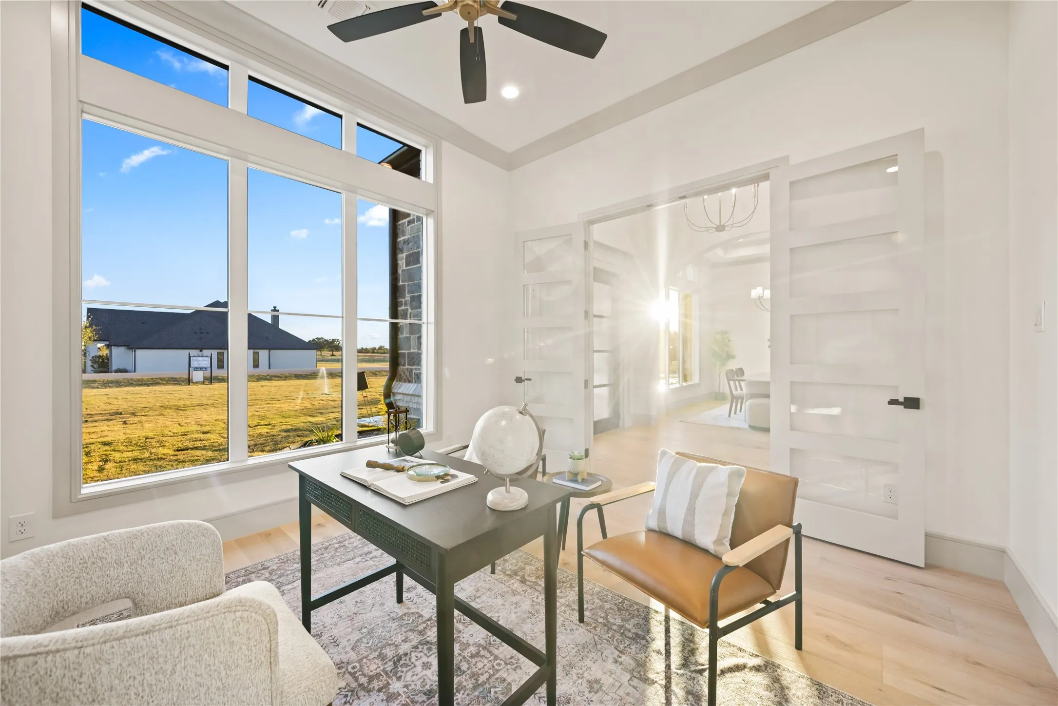 Dedicated room with expansive multi-pane windows, light wood-finish flooring, and a ceiling fan