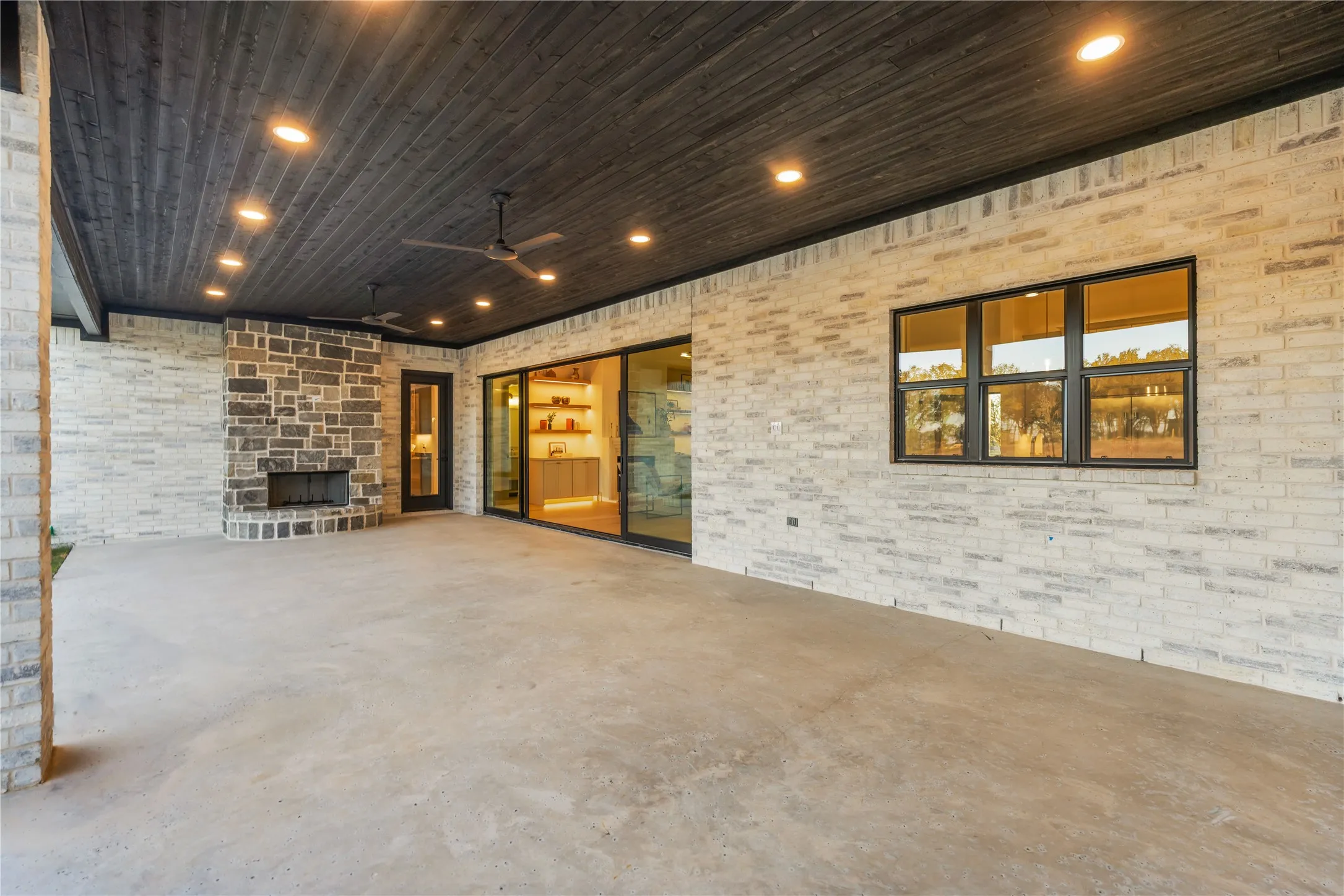 Expansive outdoor living area featuring a wood-plank ceiling with recessed lighting and ceiling fans