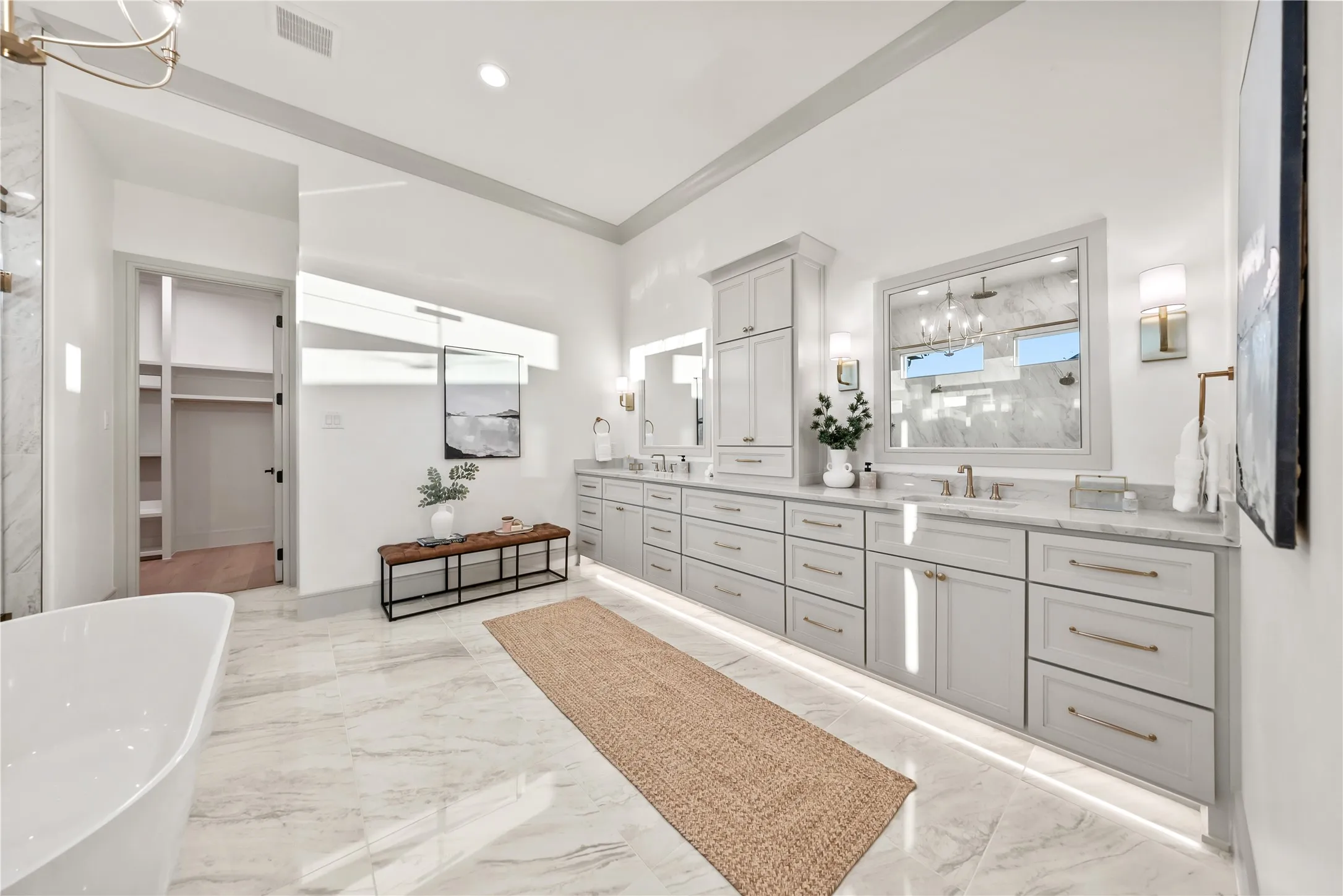 Dual vanity featuring light gray cabinetry with gold-finish hardware, undermount sinks, and stone countertops