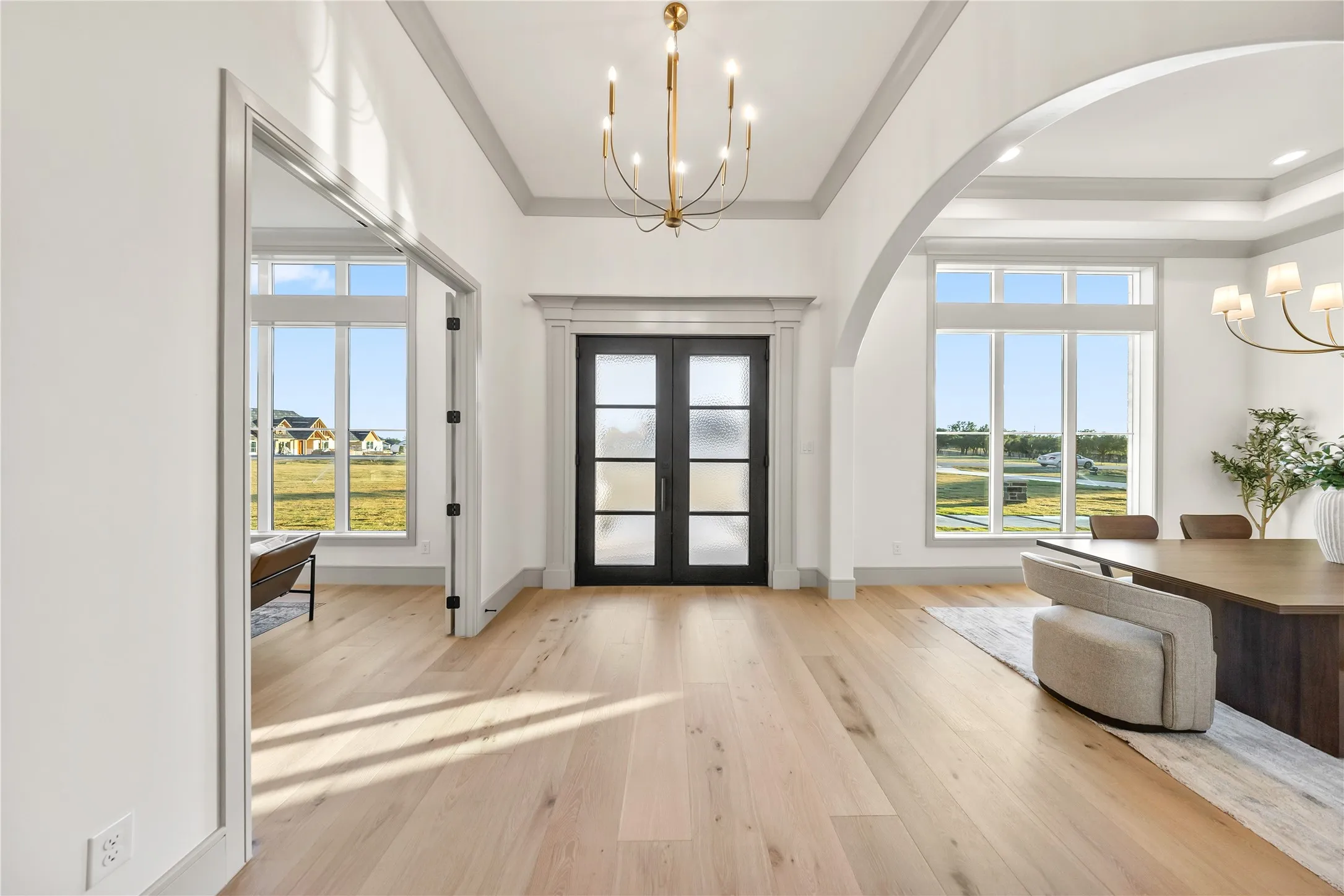 Entryway featuring light wood-finish flooring, a contemporary chandelier, and a black double-door entry