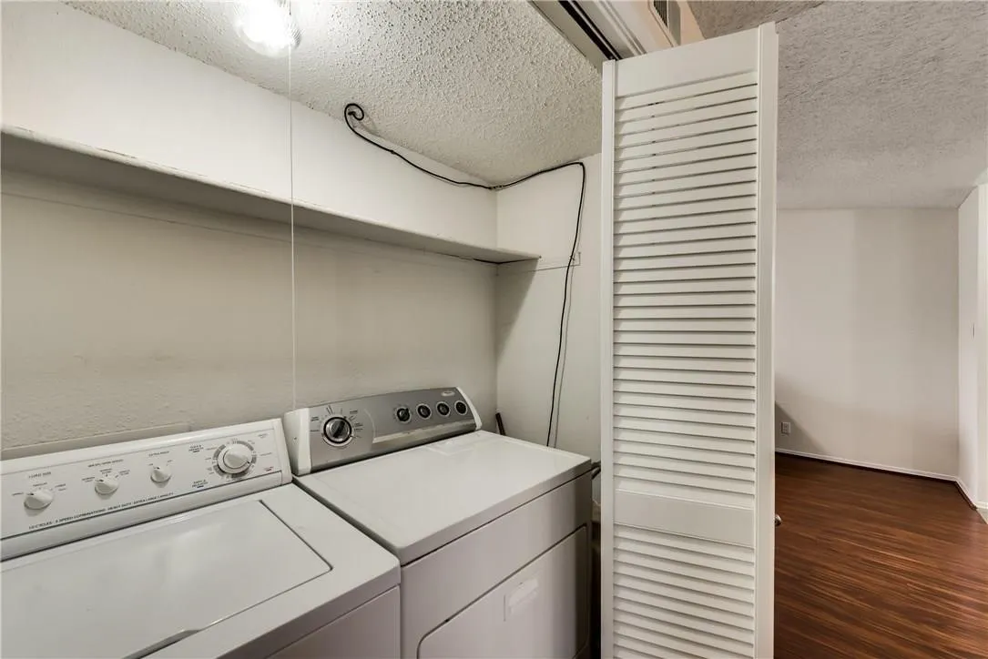 Washroom featuring dark hardwood / wood-style floors, a textured ceiling, and independent washer and dryer