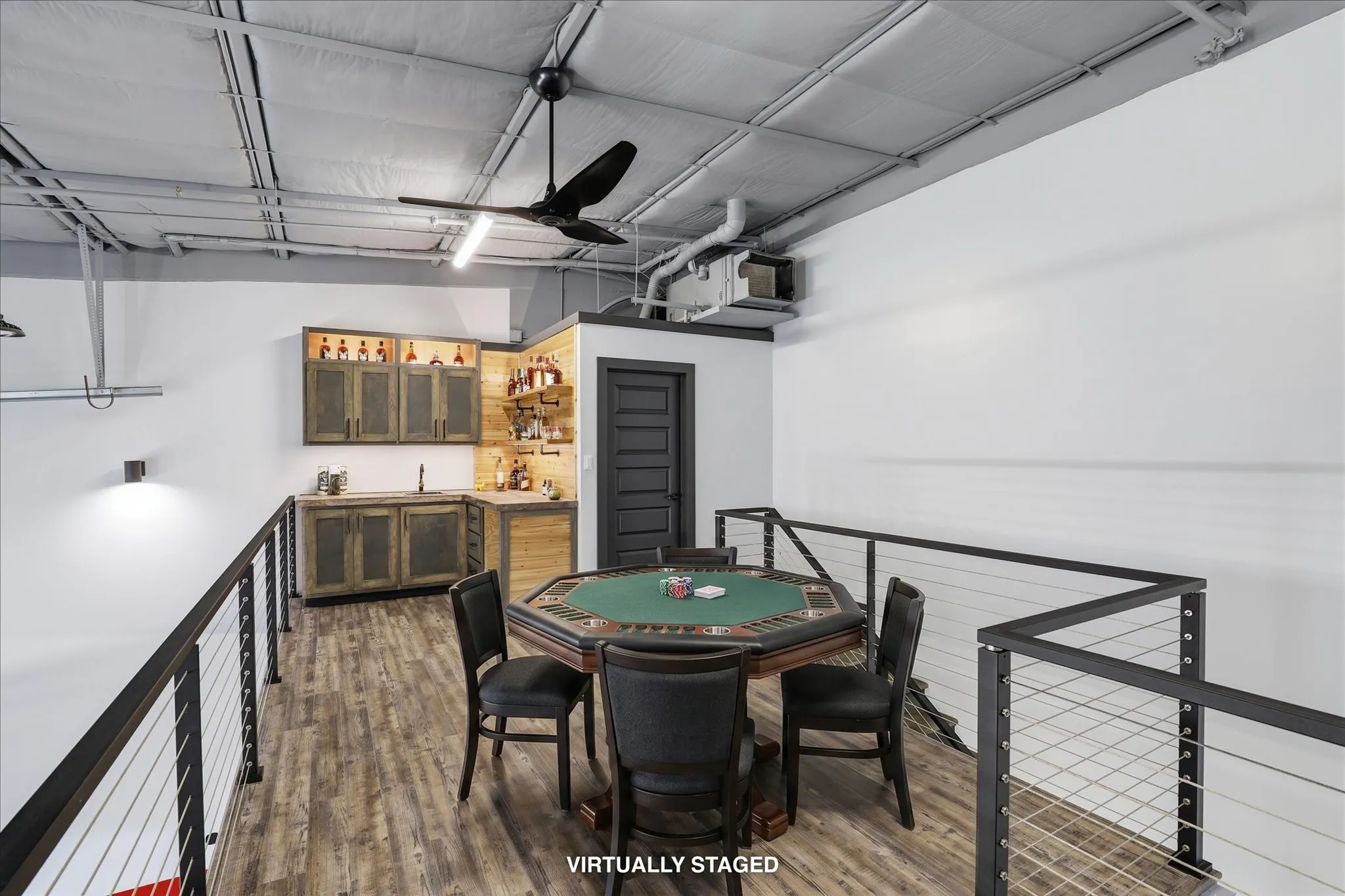 Upper-level open space featuring wood-finish flooring and a built-in wet bar with wood cabinetry (virtually staged with furniture)