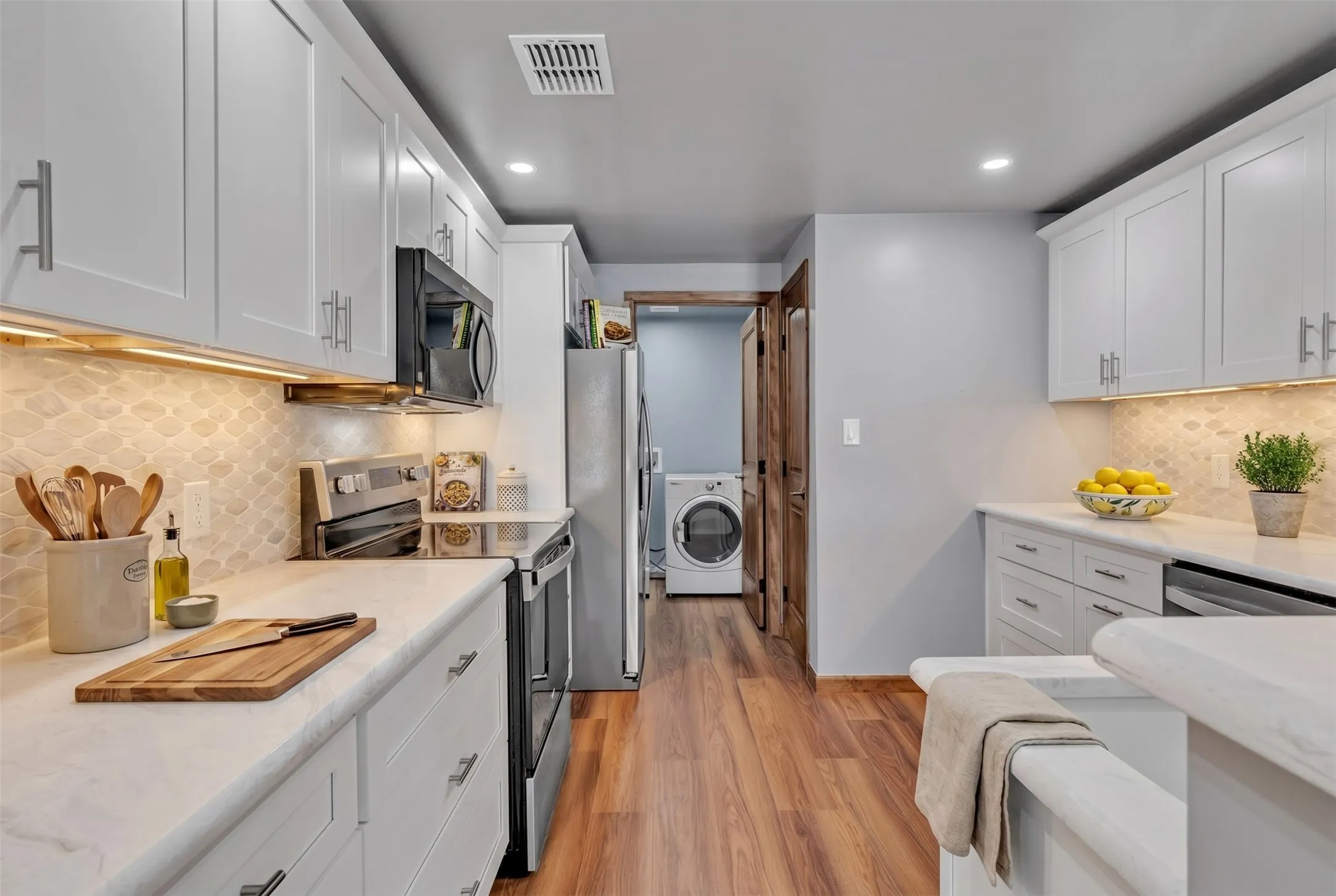 Kitchen includes quartz counters, stainless appliances including refrigerator. Utility room includes washer and dryer.