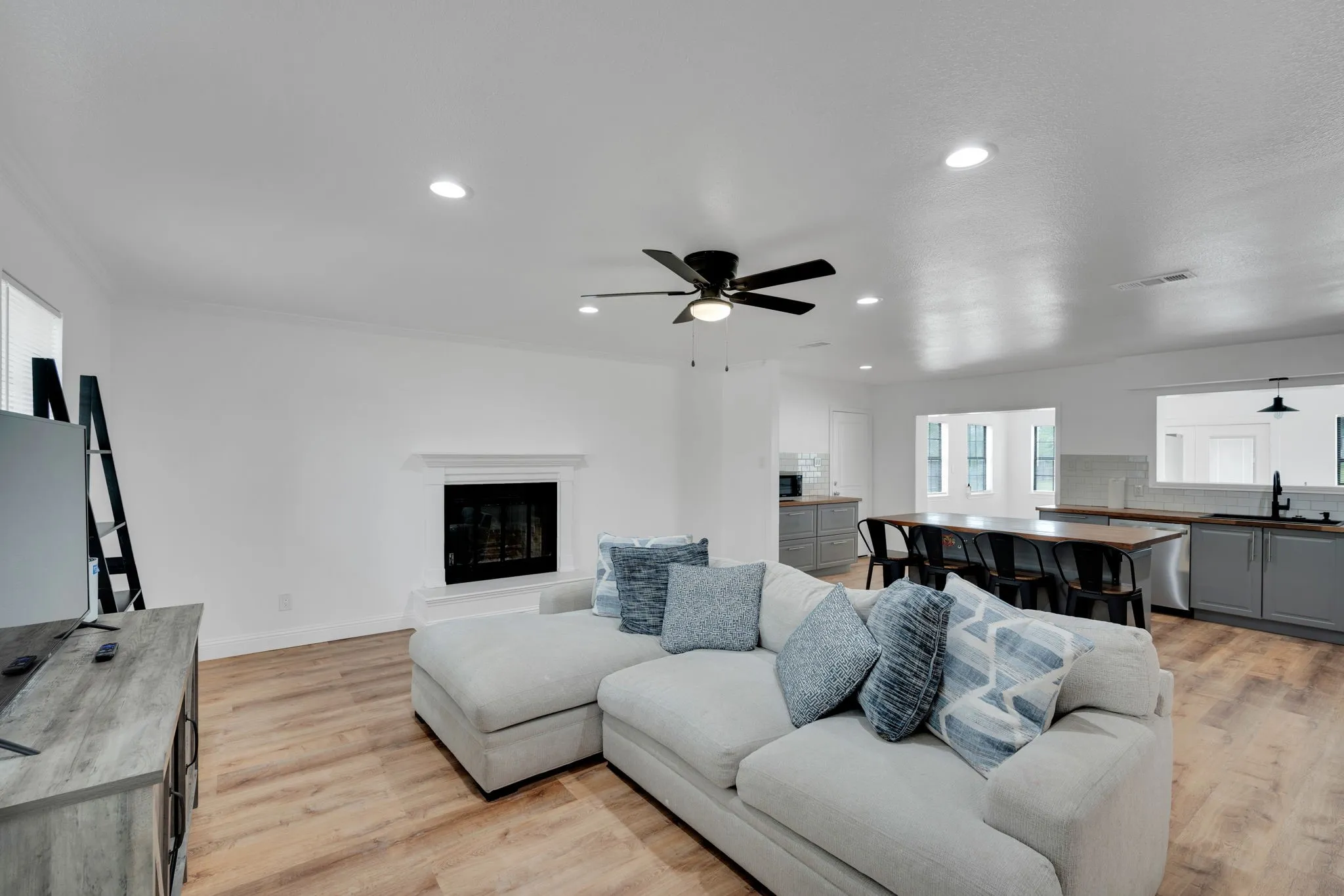 Open-concept living area featuring wood-finish flooring, recessed lighting, and a modern fireplace with a white mantel
