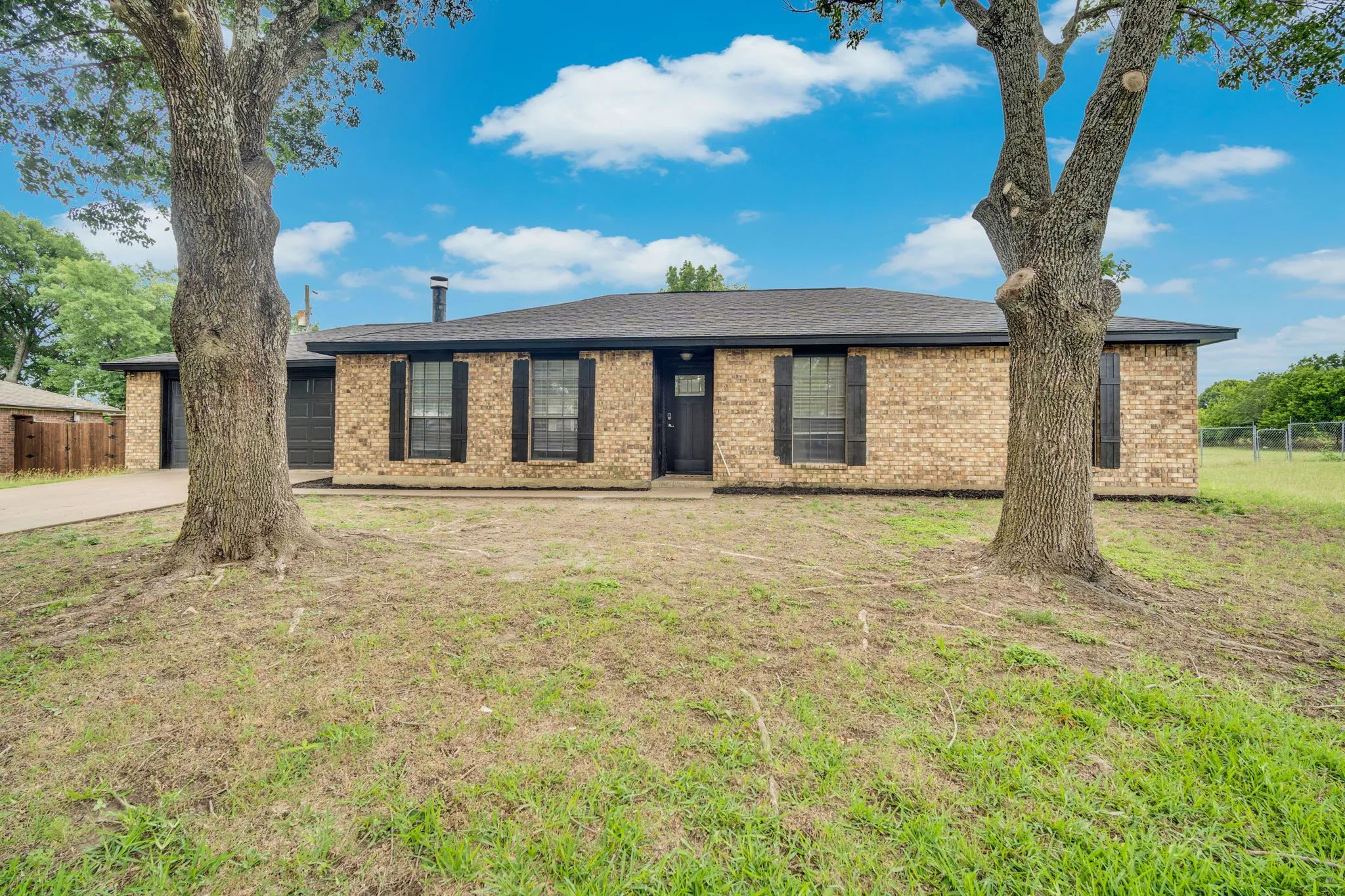 Single-story brick exterior with a dark shingle roof and black window shutters