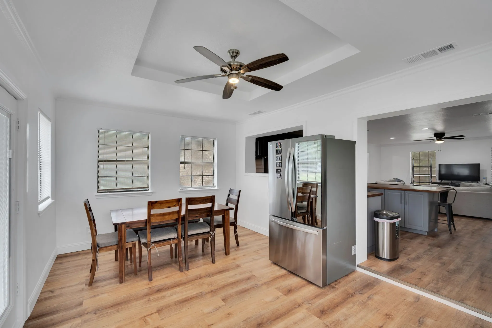 Dining area featuring wood-finish flooring, a tray ceiling with a ceiling fan, and multiple windows