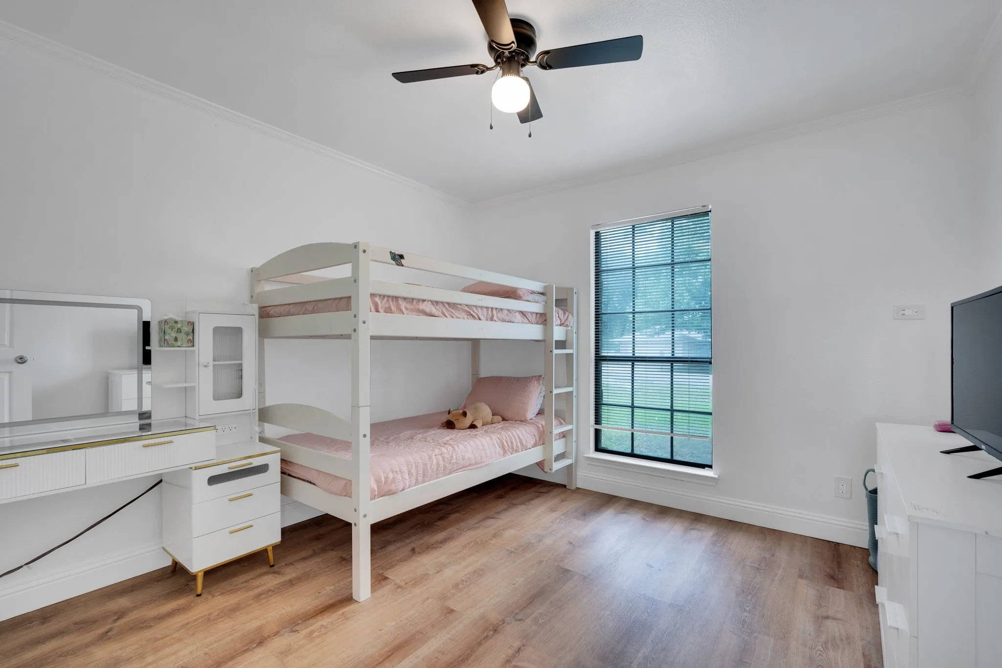 Room featuring wood-finish flooring, a ceiling fan with integrated lighting, and crown molding