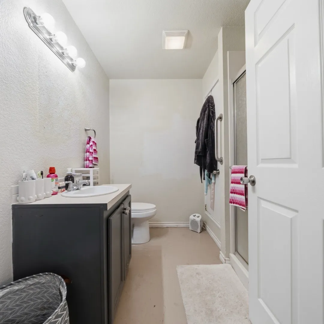 Bathroom with a white vanity sink, dark cabinetry, and a shower enclosure