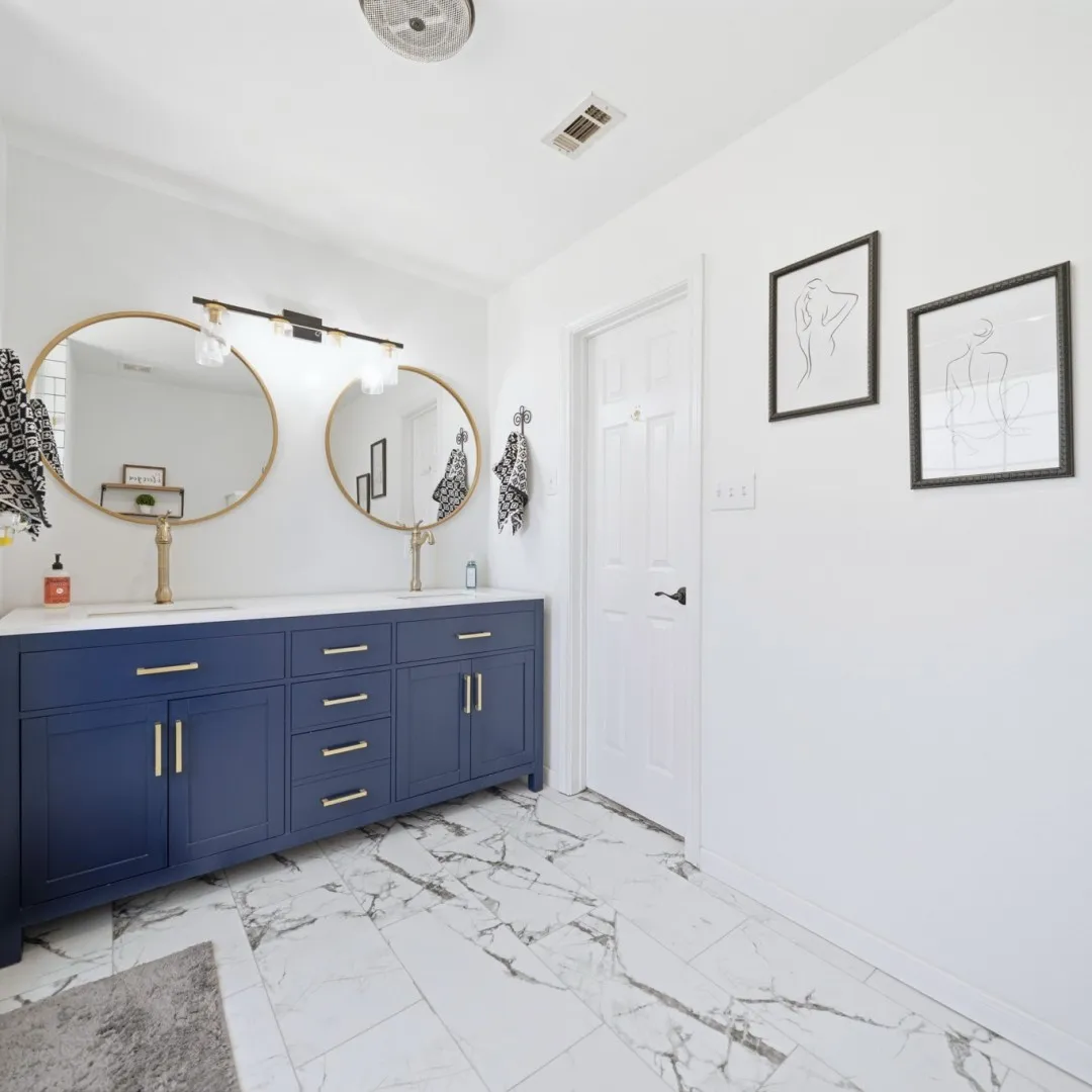 Double vanity featuring a deep blue finish, gold hardware, and a white countertop