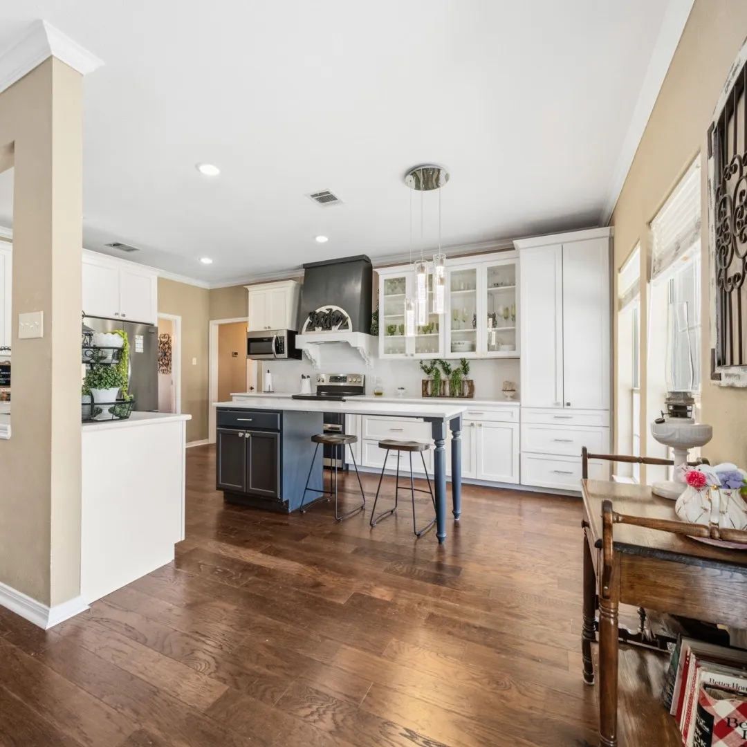 Kitchen featuring wood-finish flooring, white cabinetry, a central island with seating, a pendant light fixture, and recessed lighting