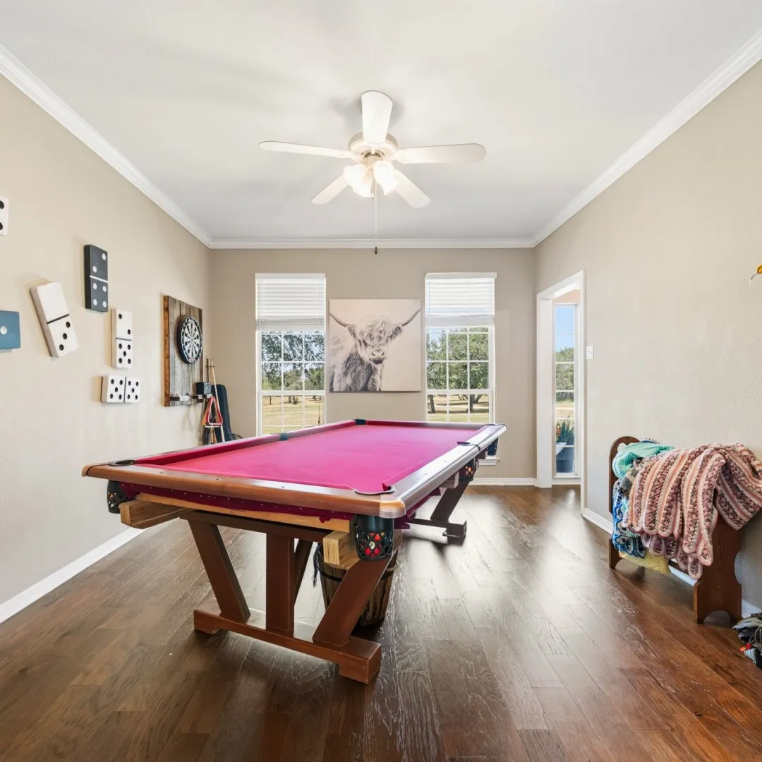 Spacious room featuring wood-finish flooring, crown molding, and a ceiling fan