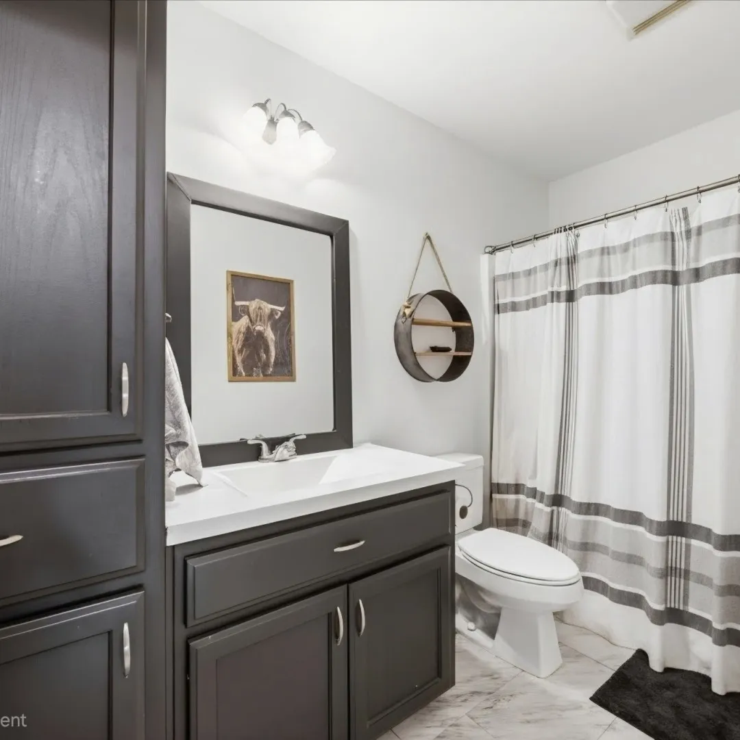 Bathroom vanity featuring dark cabinetry, an integrated sink, and white countertop