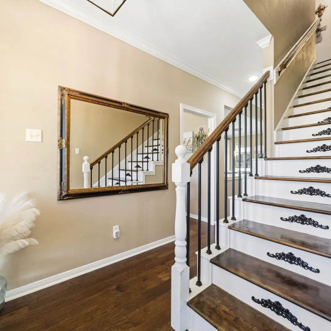 Staircase featuring dark wood-finish treads, white risers, and decorative black iron​​‌​​​​‌​​‌‌​‌‌​​​‌‌​‌​‌​‌​​​‌​​ accents