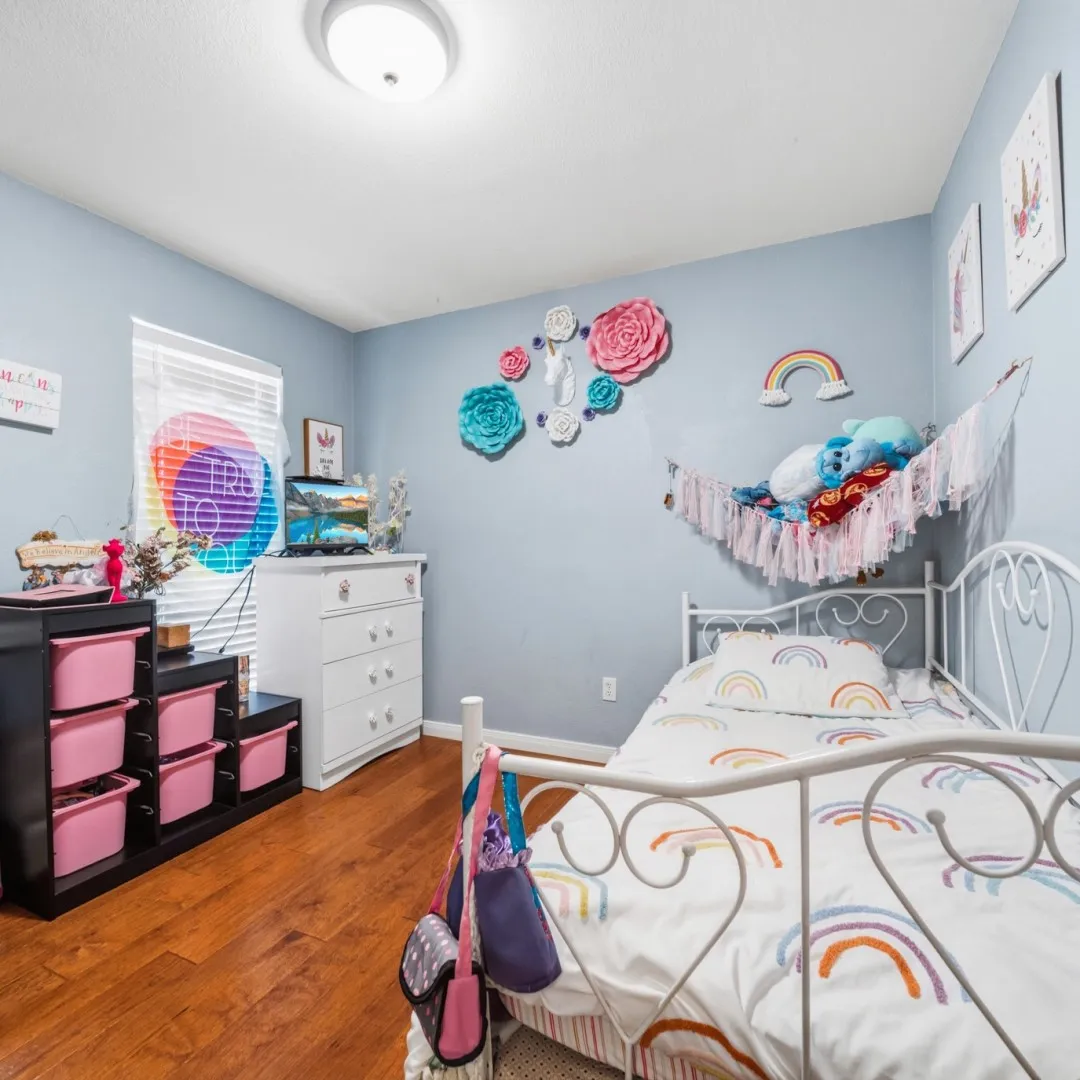 Bedroom featuring wood-finish flooring, a white metal bed frame, and a flush-mount ceiling light fixture