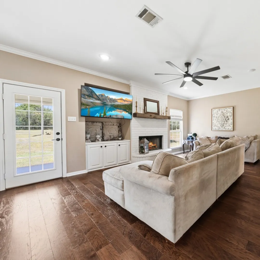 Living area featuring wood-finish flooring, a white painted brick fireplace with a wood mantel, recessed lighting, and a multi-blade ceiling fan