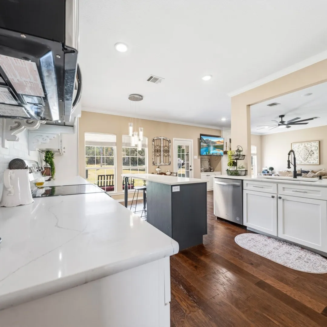Modern kitchen featuring white cabinetry, light countertops, an eat-at island with a dark base, stainless steel appliances, and wood-finish flooring