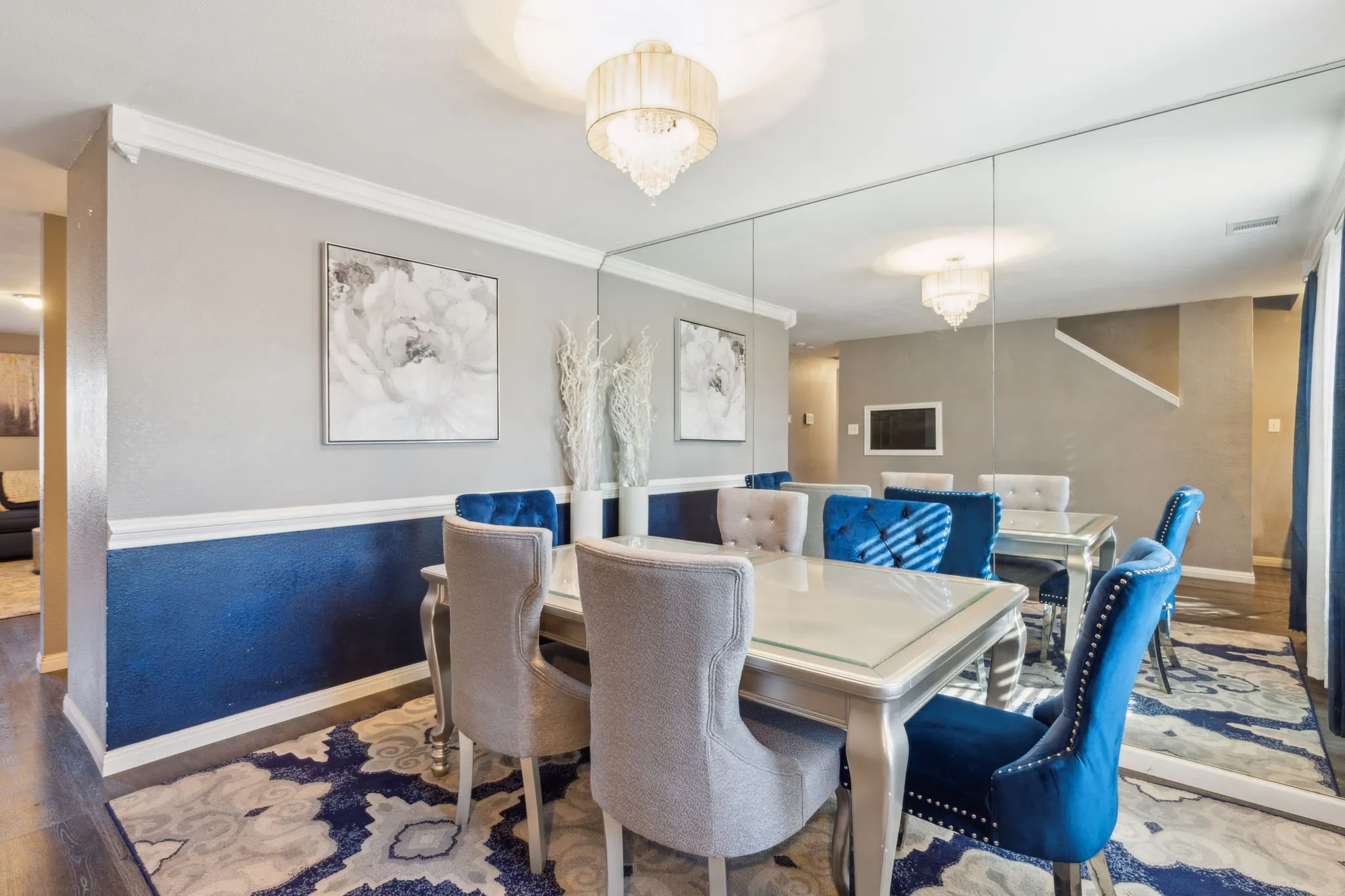 A perfect formal dining or living area equipped with a accent mirror wall, chair rail and chandelier.