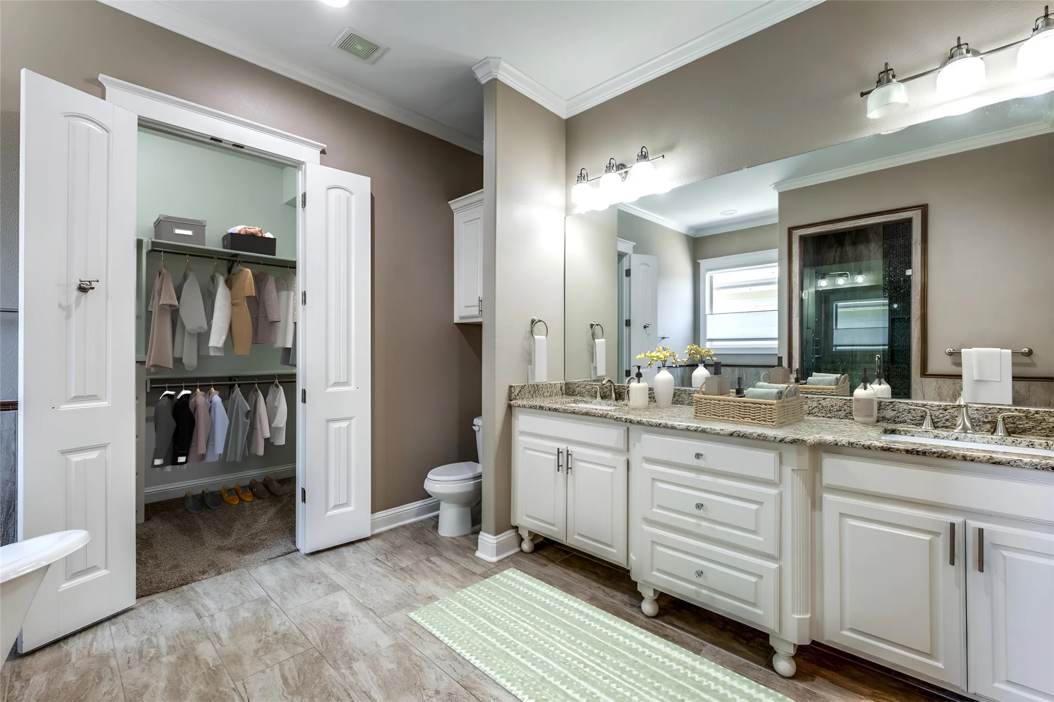 Bathroom featuring a double vanity with granite countertops, wood-finish flooring, and a walk-in closet with double bifold doors