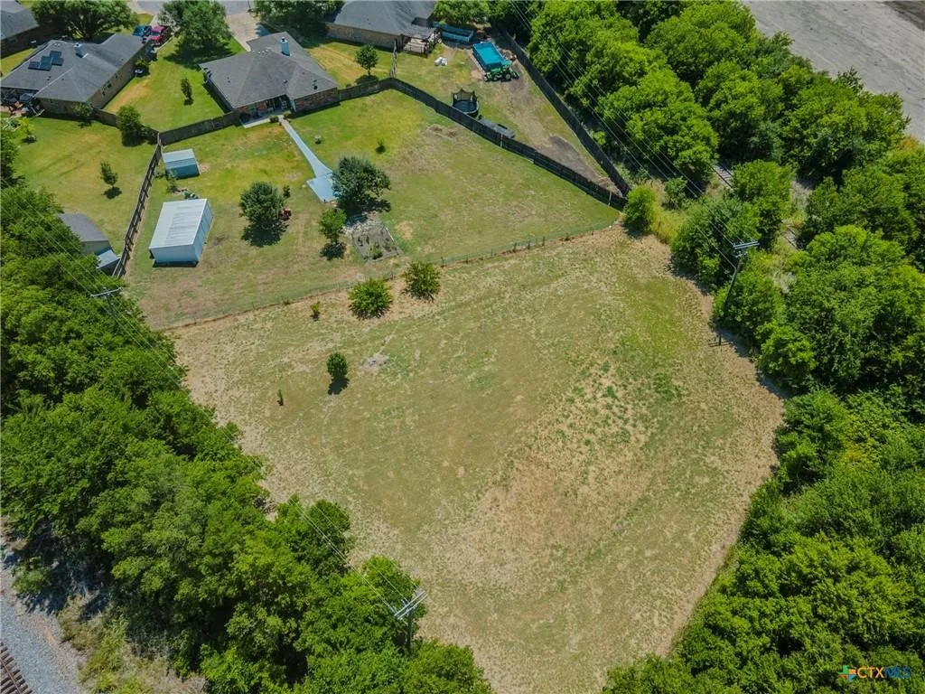 Expansive open land area surrounded by mature trees, featuring a clear, level terrain
