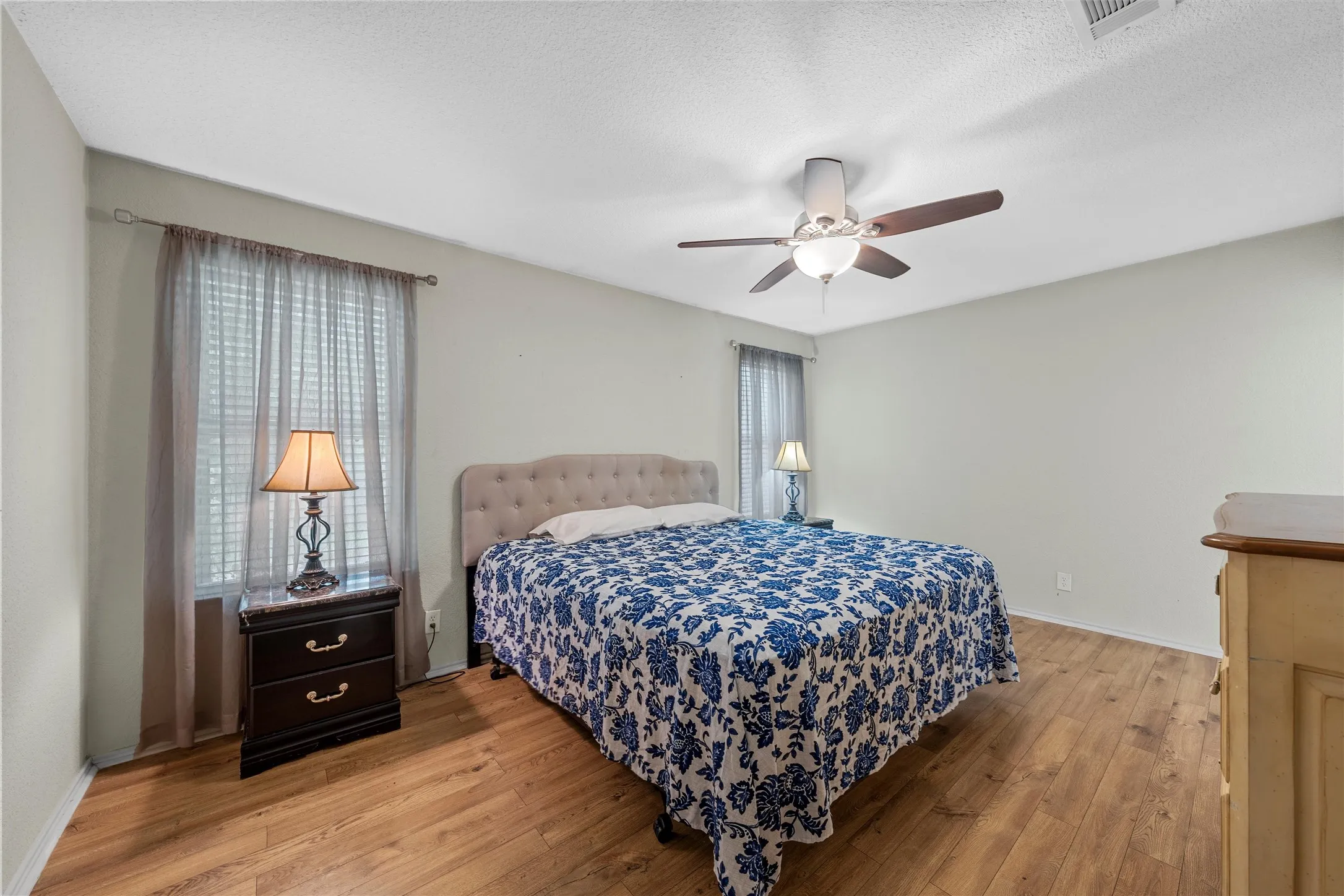 Room featuring wood-finish flooring, light-toned walls, and a ceiling fan with integrated lighting
