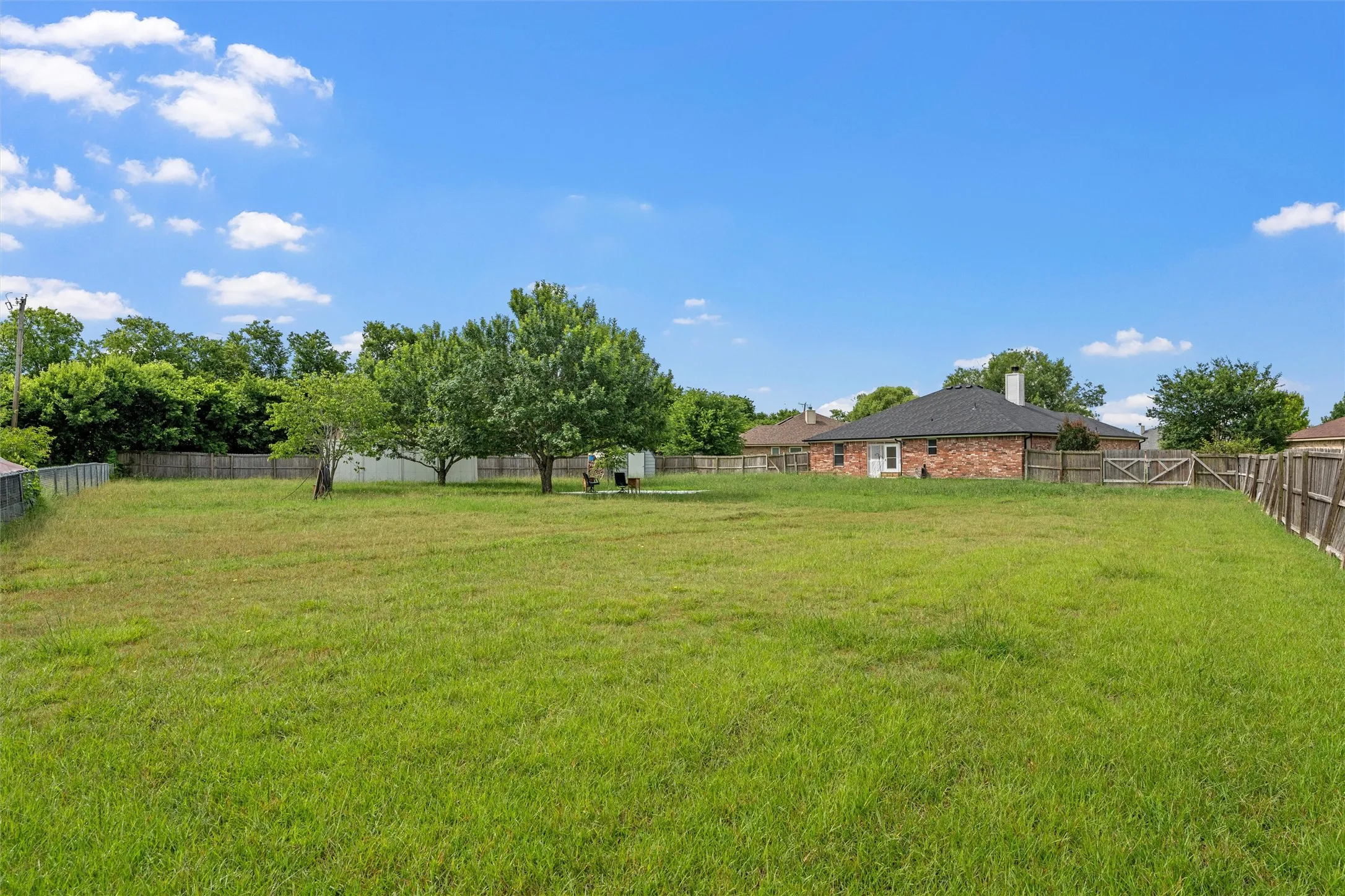 Expansive green space featuring mature trees and a perimeter fence