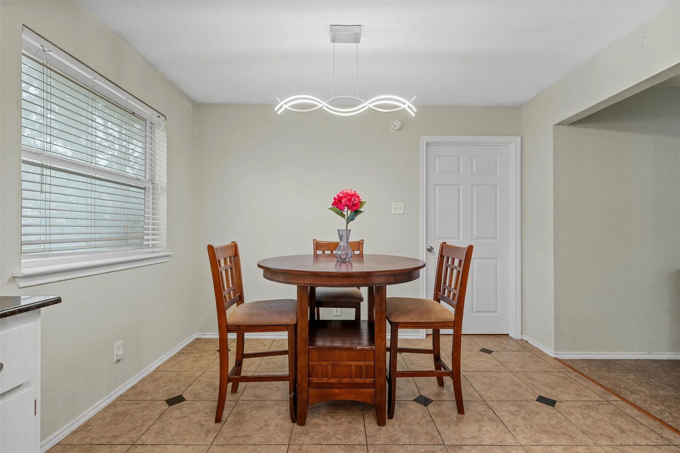 Bright dining area featuring tile flooring with dark accent squares and a contemporary linear light fixture