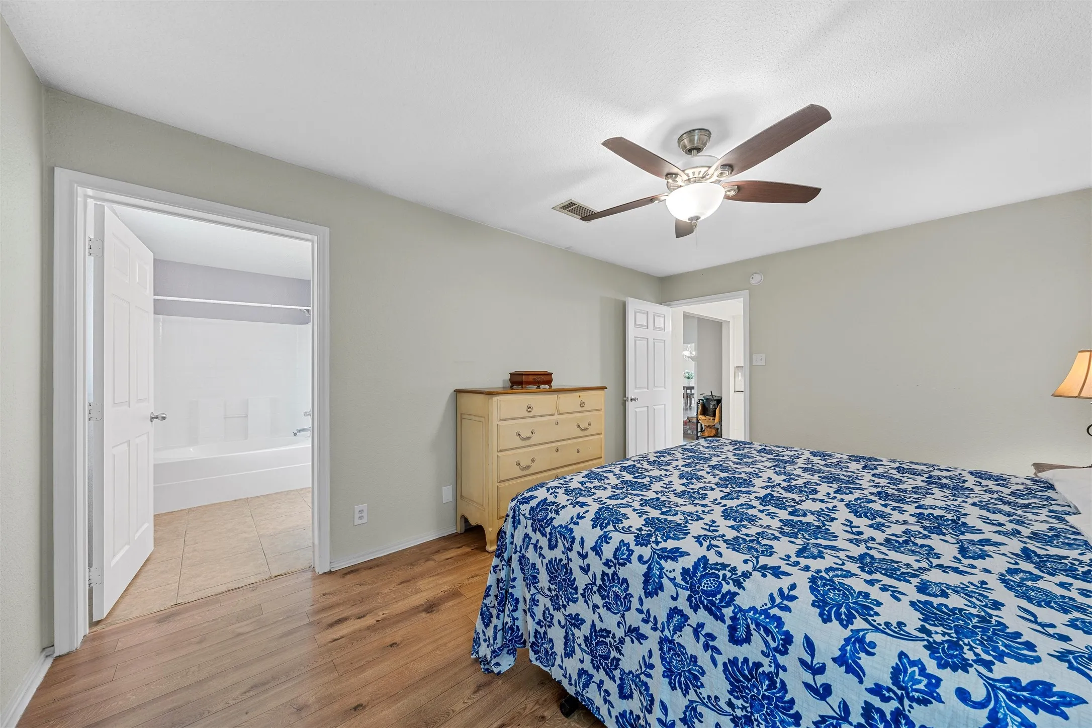 Bedroom featuring wood-finish flooring, a ceiling fan with integrated lighting, and light gray wall paint