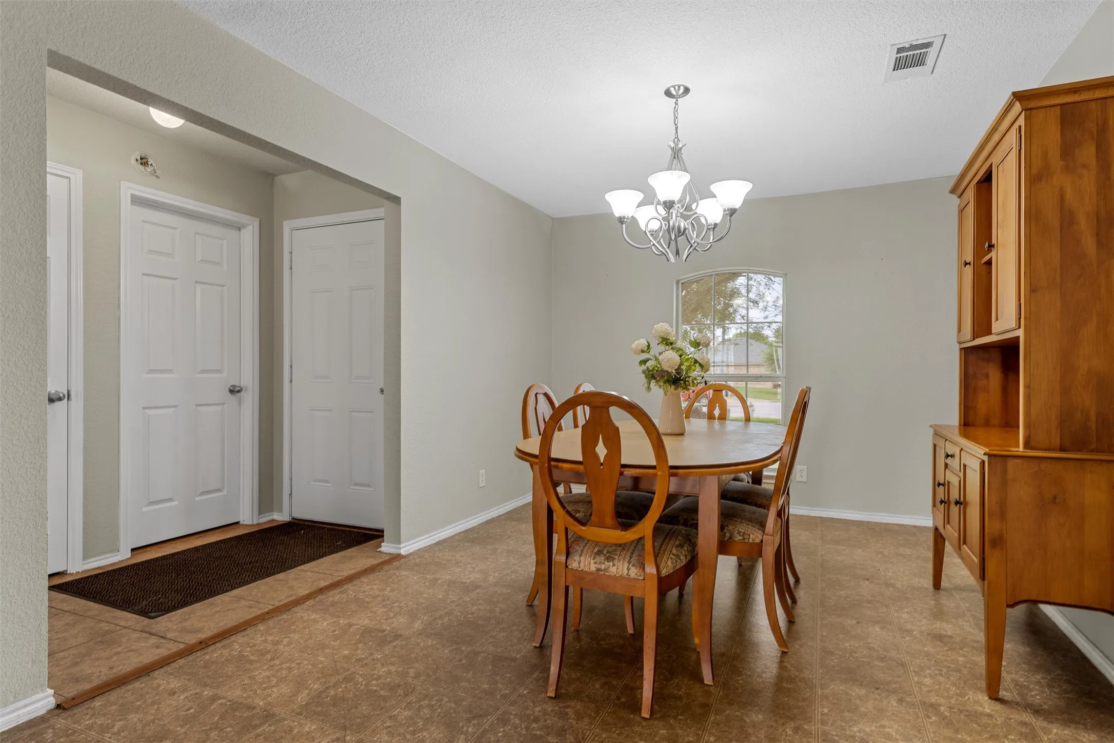Dining area featuring neutral wall tones, a large window, a multi-bulb chandelier, and wood-finish flooring