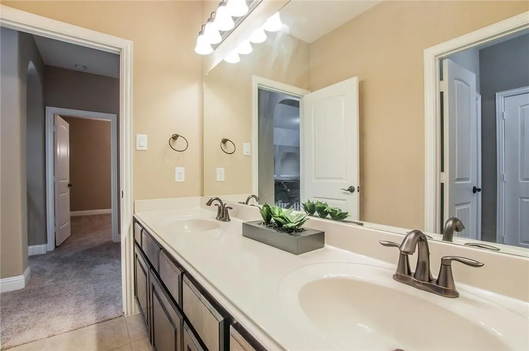 Bathroom featuring a double vanity with white countertops, integrated sinks, and bronze-finish fixtures