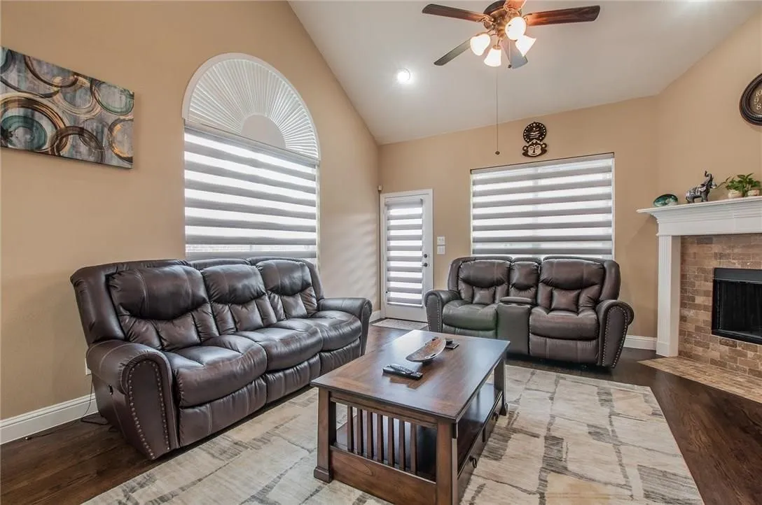 Living area featuring vaulted ceilings, a ceiling fan with integrated lighting, and dark wood-finish flooring