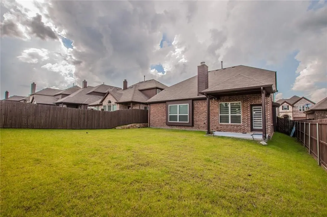 Expansive backyard featuring a lush lawn, a privacy fence, and a covered patio with a contemporary door
