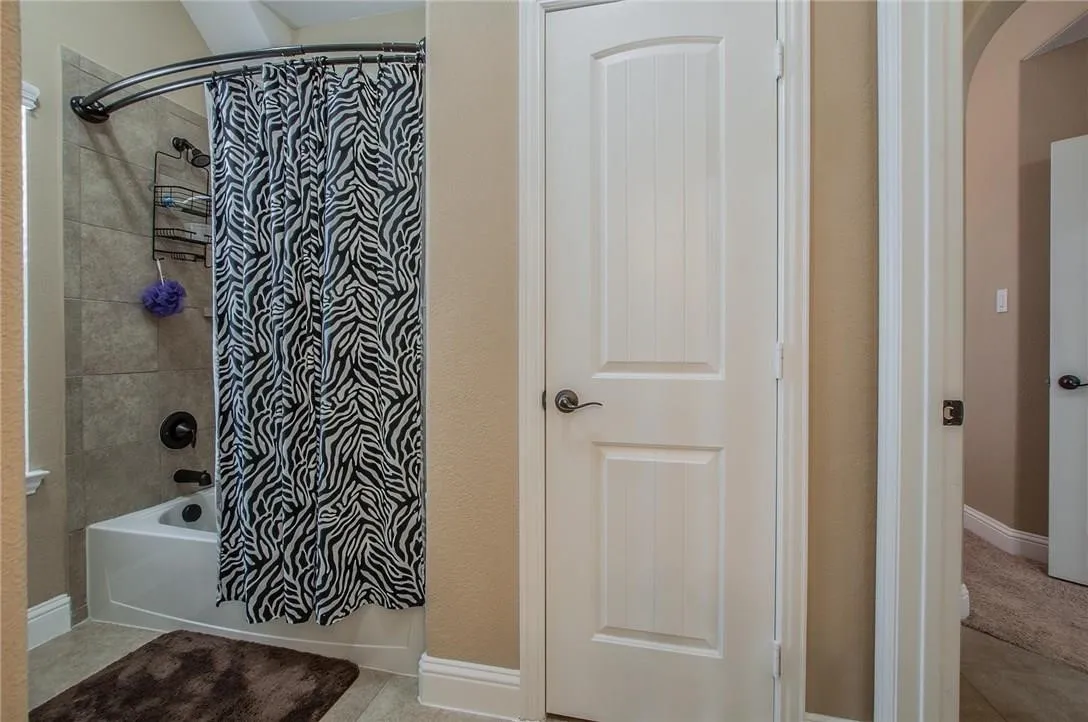 Bathroom featuring a tub and shower combination with tiled walls, matte black fixtures, and a curved shower rod