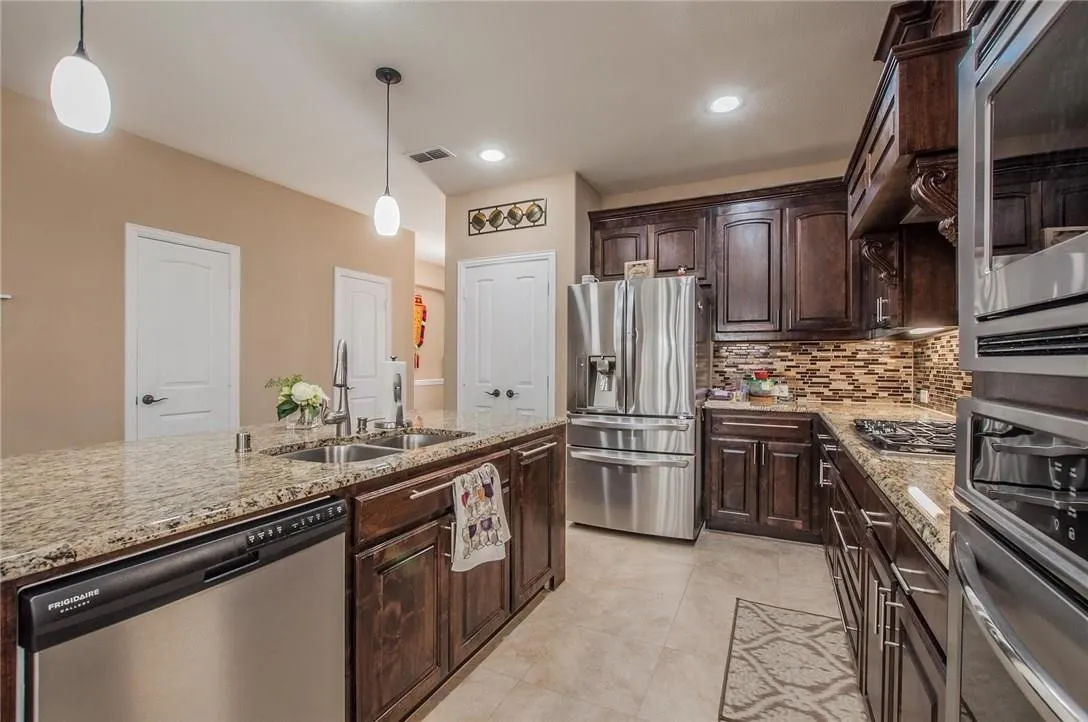 Kitchen featuring a central island with an undermount double-basin sink and stainless steel dishwasher