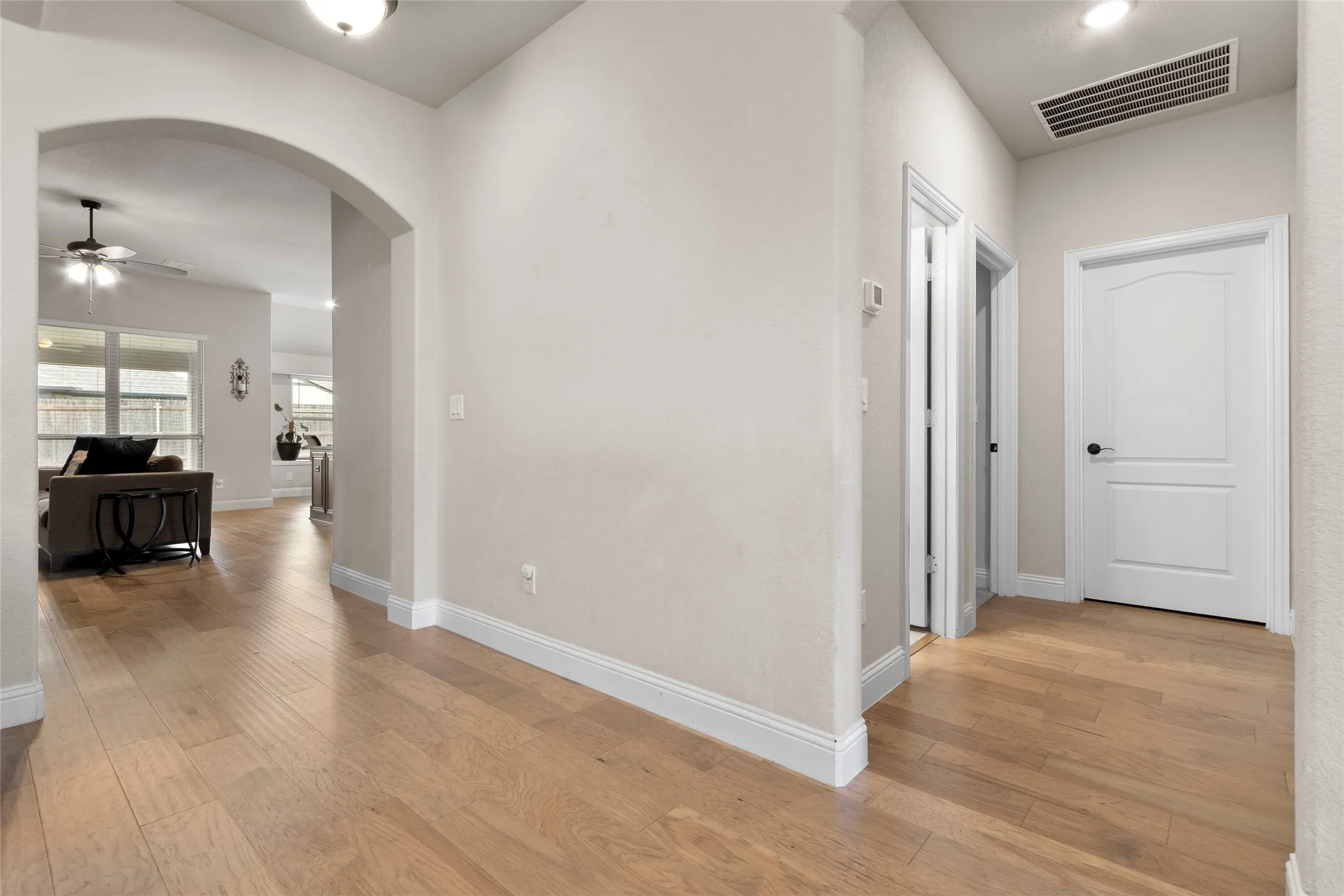 Hallway featuring light wood-finish flooring, white baseboards, and neutral wall tones