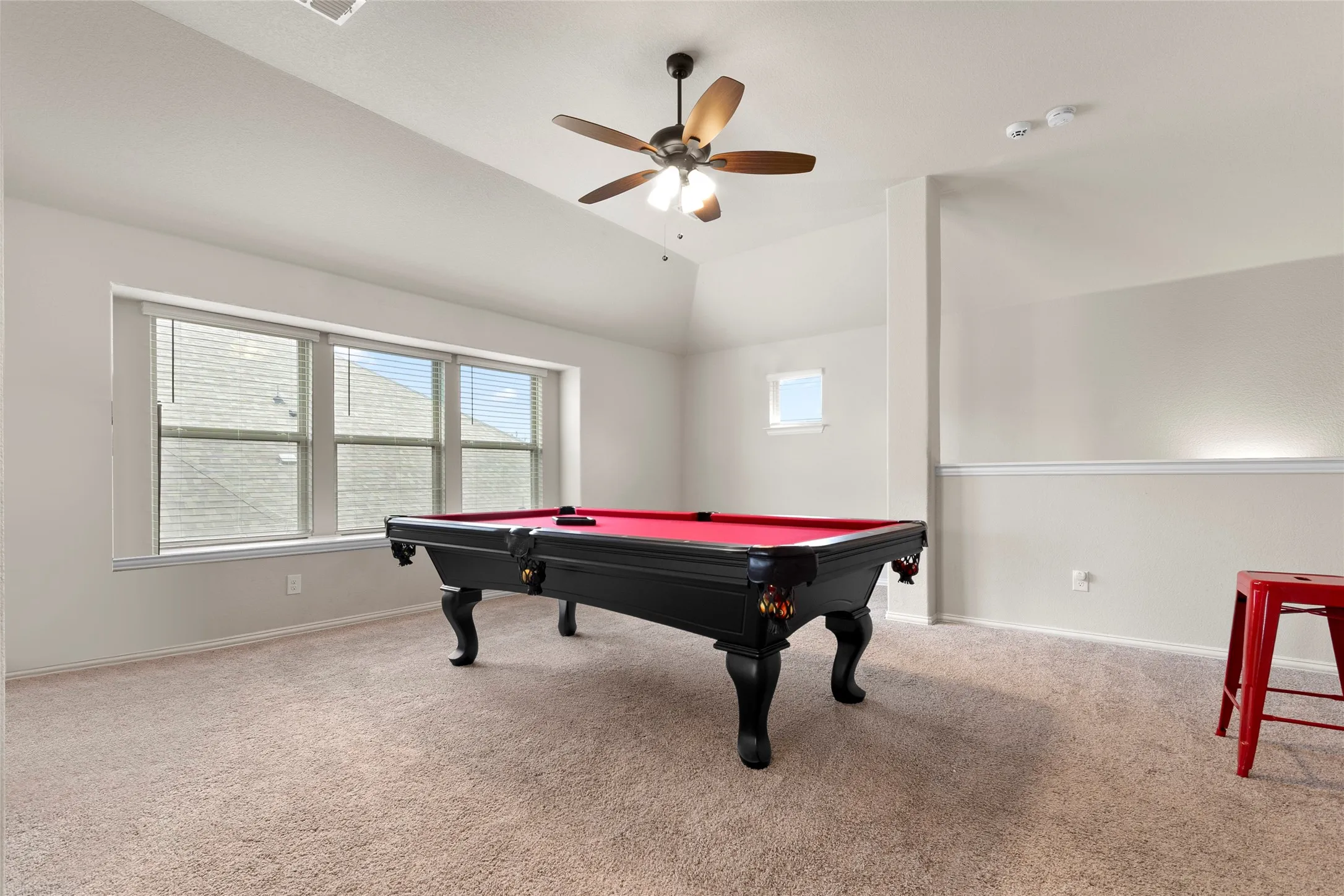 Spacious room with vaulted ceiling and neutral carpeting