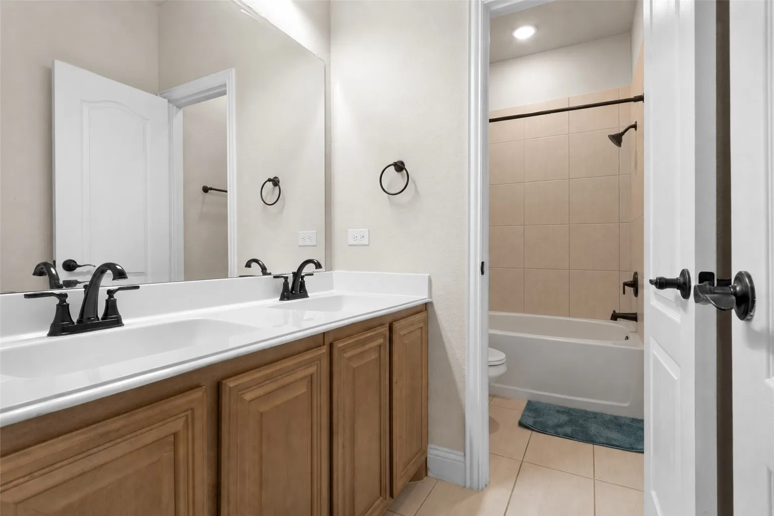 Dual vanity with white countertops, wood-finish cabinetry, and matte black fixtures