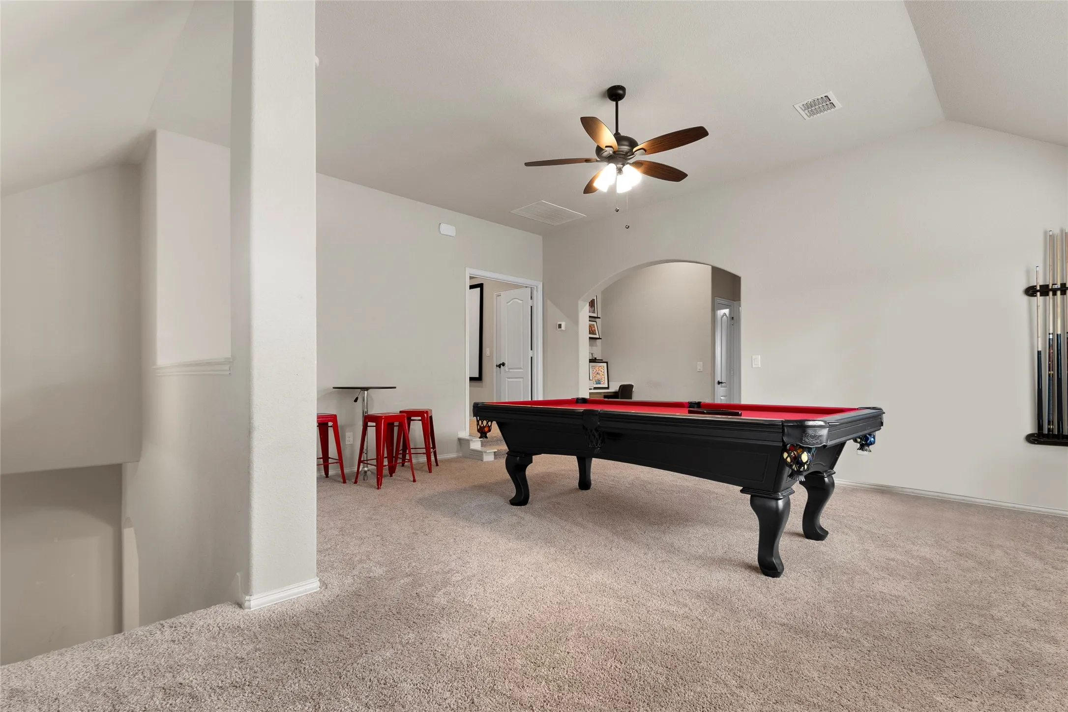Vaulted ceiling game room featuring light-toned carpet flooring and an arched doorway