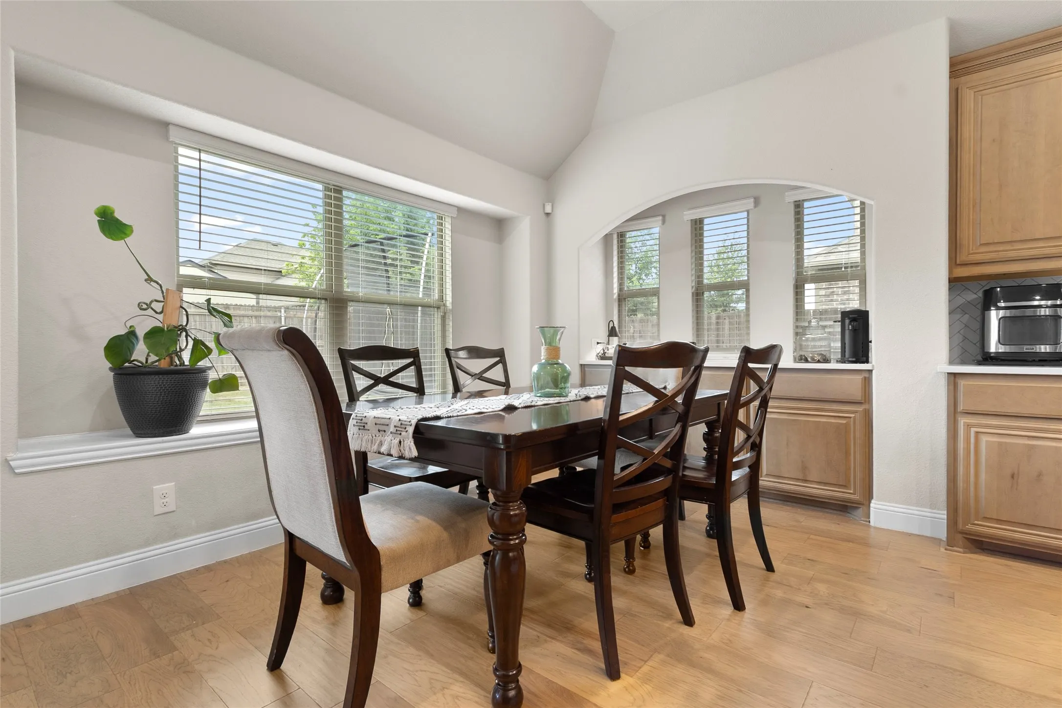 Dining area featuring wood-finish flooring, a vaulted ceiling, and a large bay window
