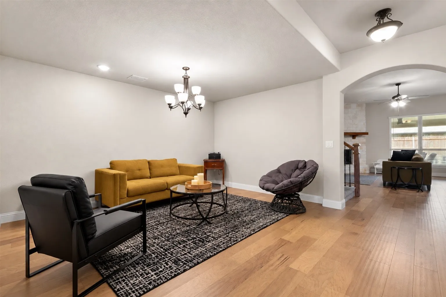 Hardwood flooring, recessed lighting, and an elegant chandelier illuminate this versatile living space