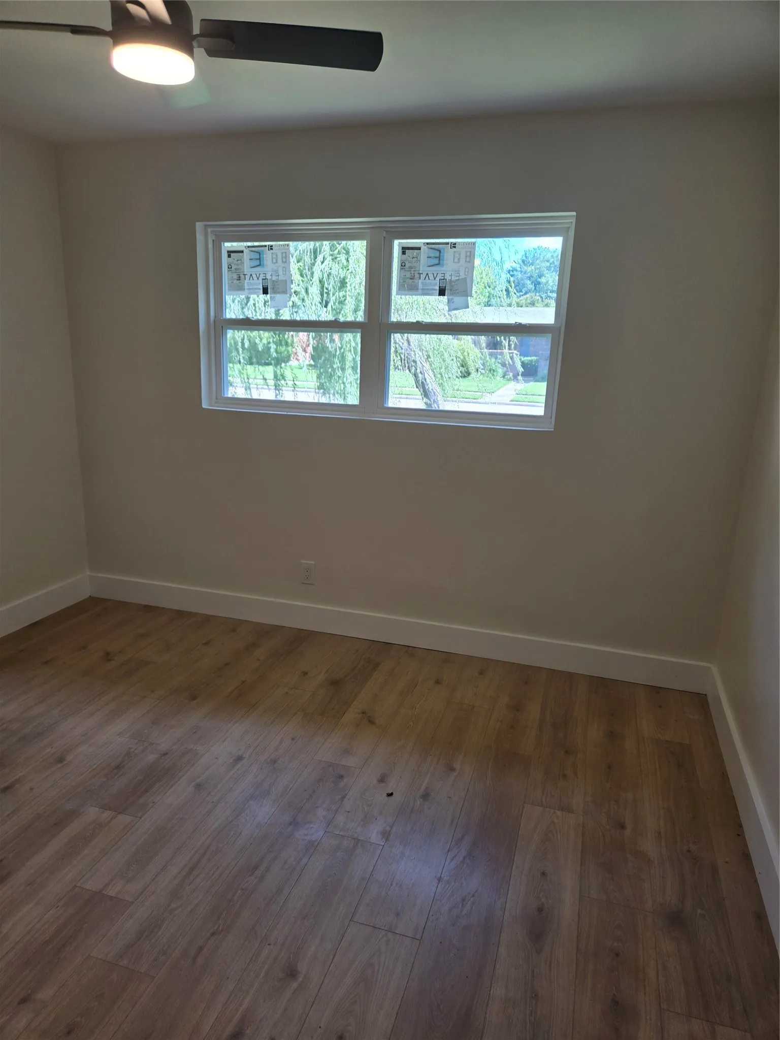 Wood-finish flooring, white trim, and a ceiling fan with integrated lighting