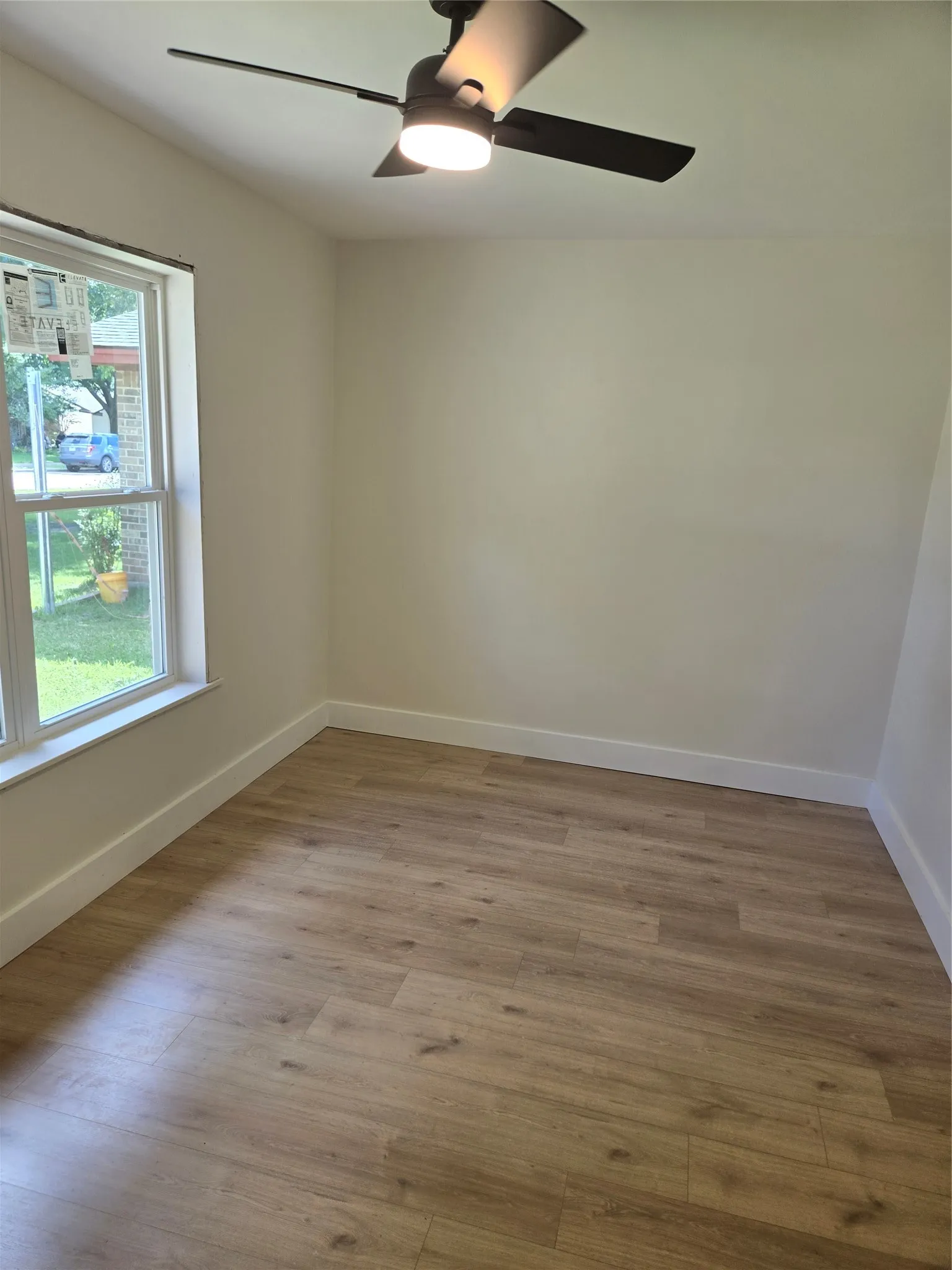 Wood-finish flooring, ceiling fan with integrated lighting, and a double-hung window