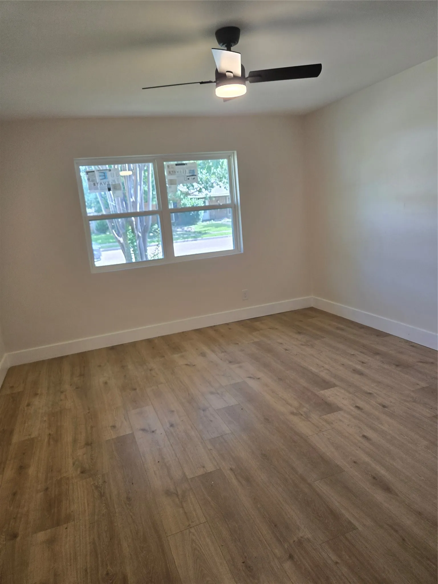 Wood-finish flooring, white walls, and a contemporary ceiling fan with integrated lighting