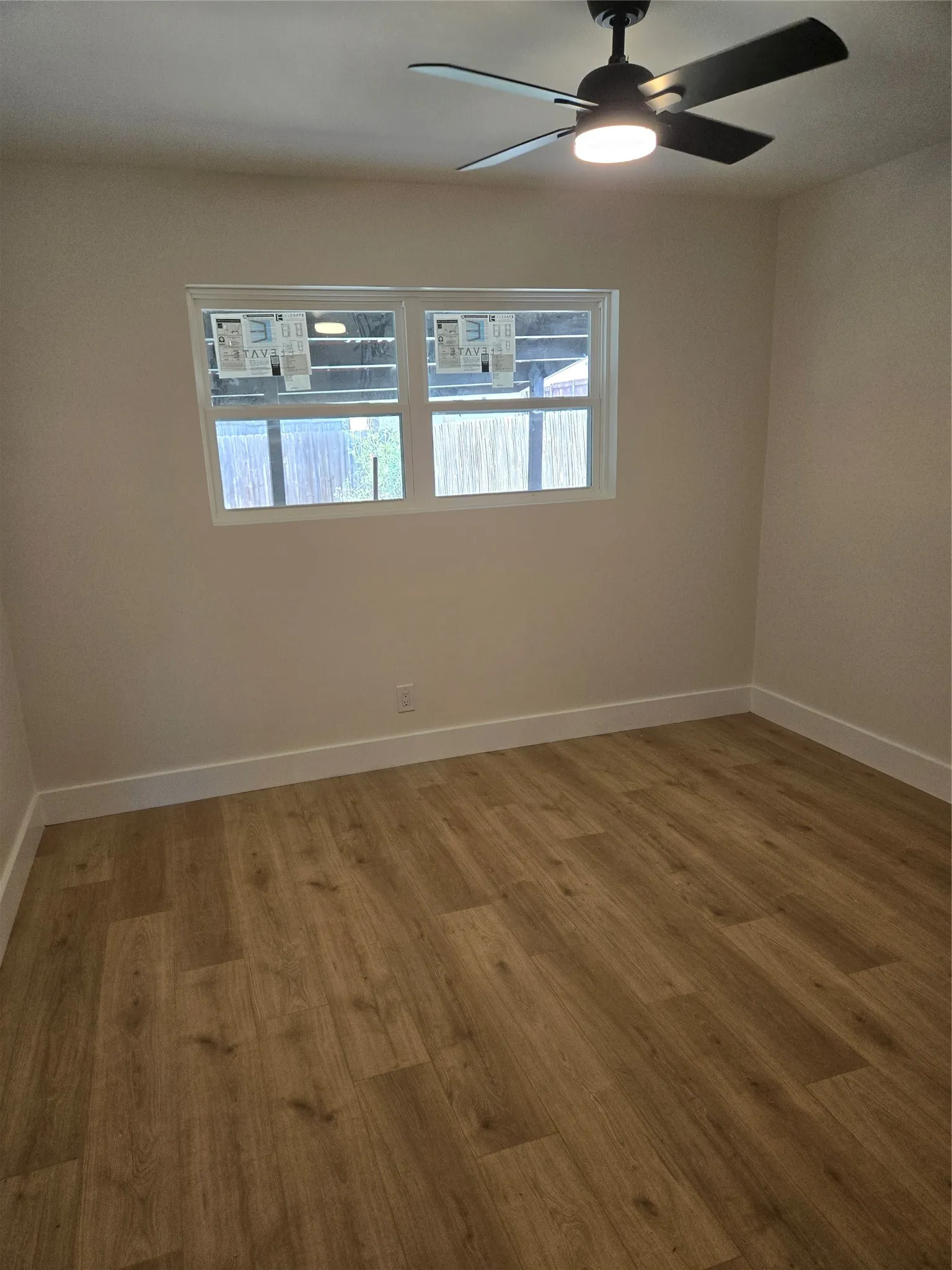 Recessed window, wood-finish flooring, ceiling fan with integrated lighting, neutral wall tones