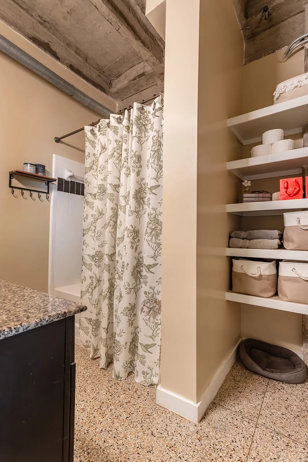 Bathroom featuring a walk-in shower with dark gray and white tile, exposed concrete ceiling, and built-in shelving