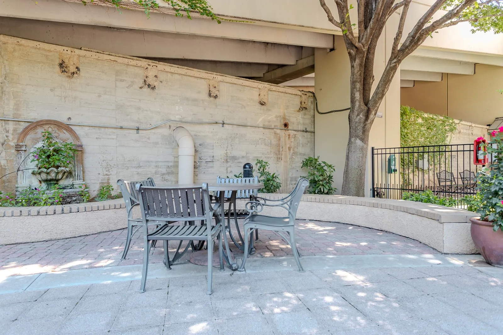 Paved patio area featuring brick-patterned hardscaping, a tiered water fountain, and curved perimeter seating