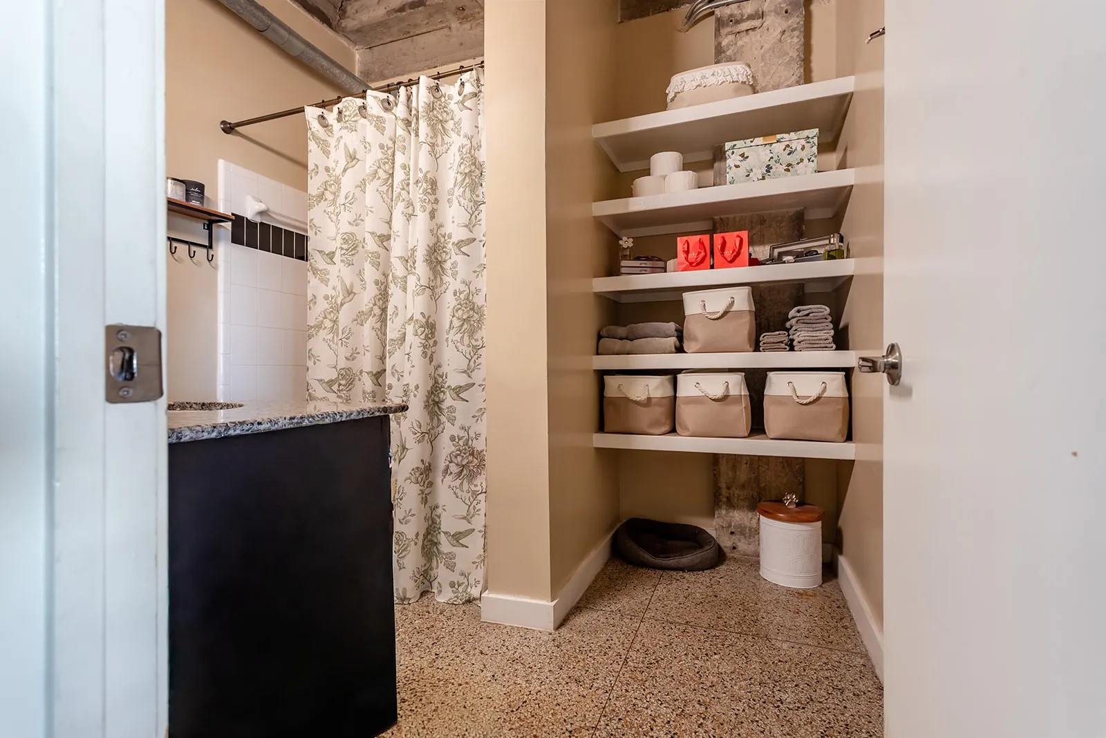 Bathroom featuring a black vanity with a speckled countertop, white subway tile shower surround with black accent tile, and a shower curtain rod