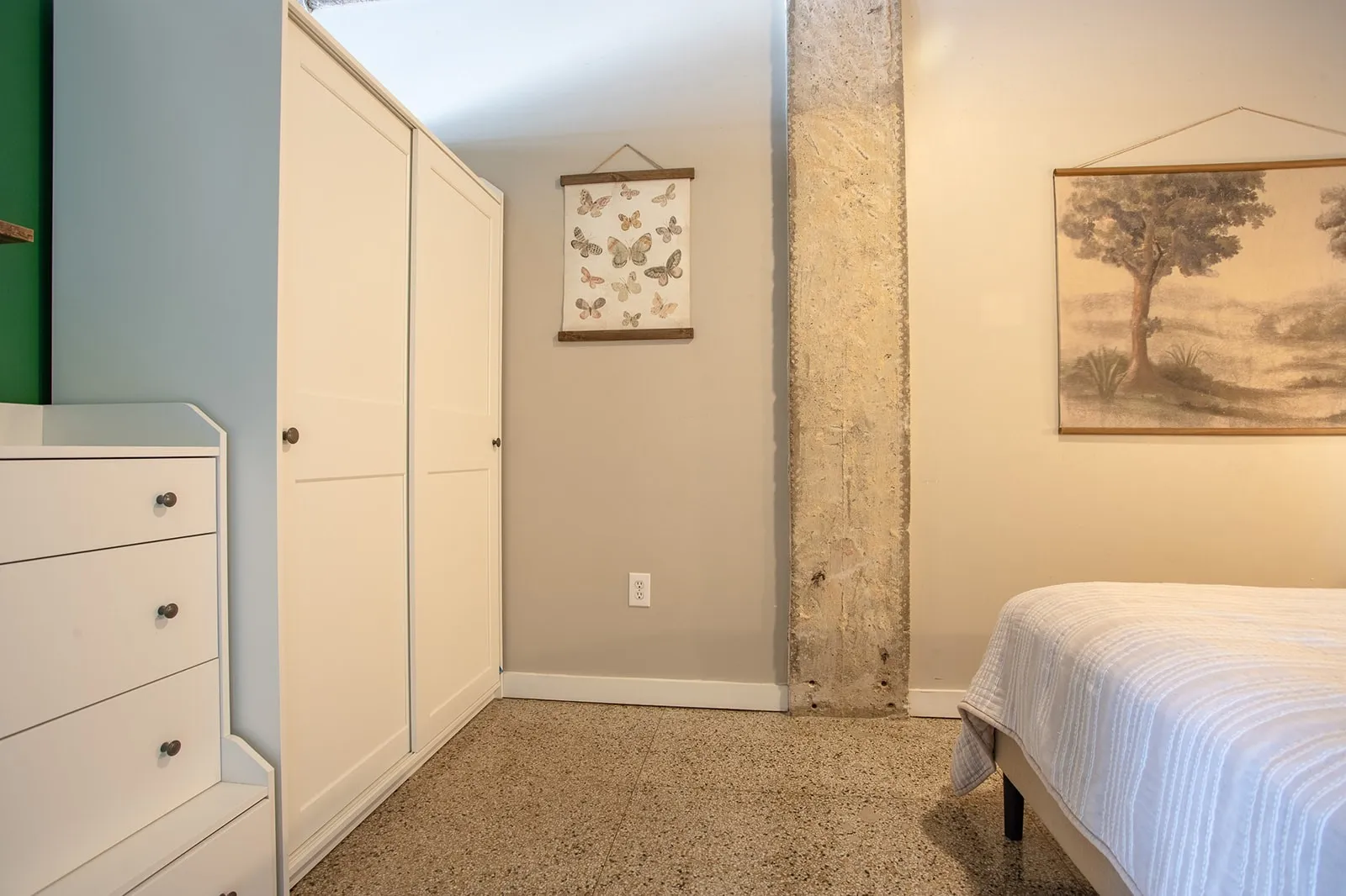 Concrete support column with exposed aggregate flooring and baseboard trim